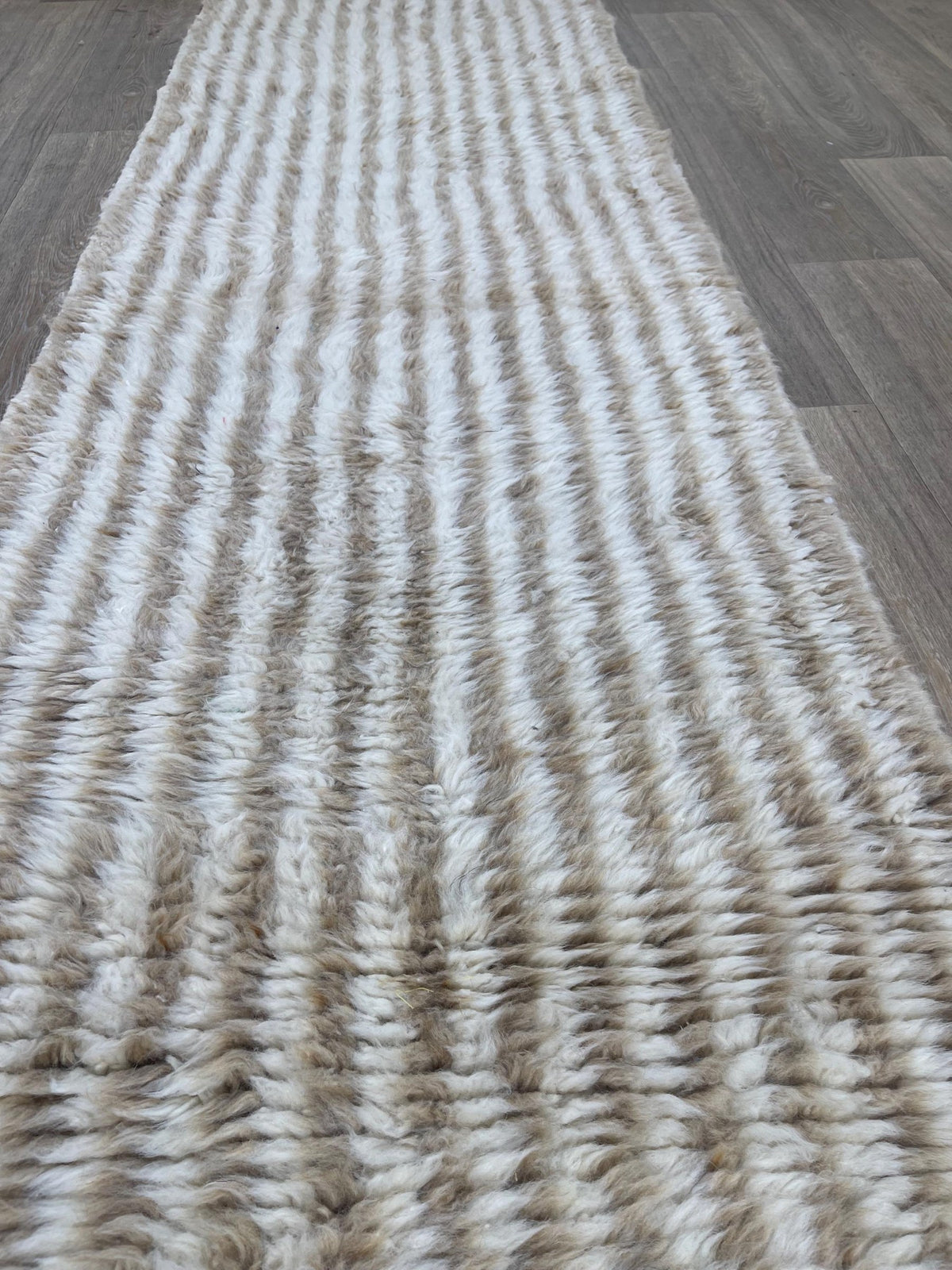 Gros plan sur un détail du tapis de couloir berbère Tamri, poil long et motif beige et blanc vus de près