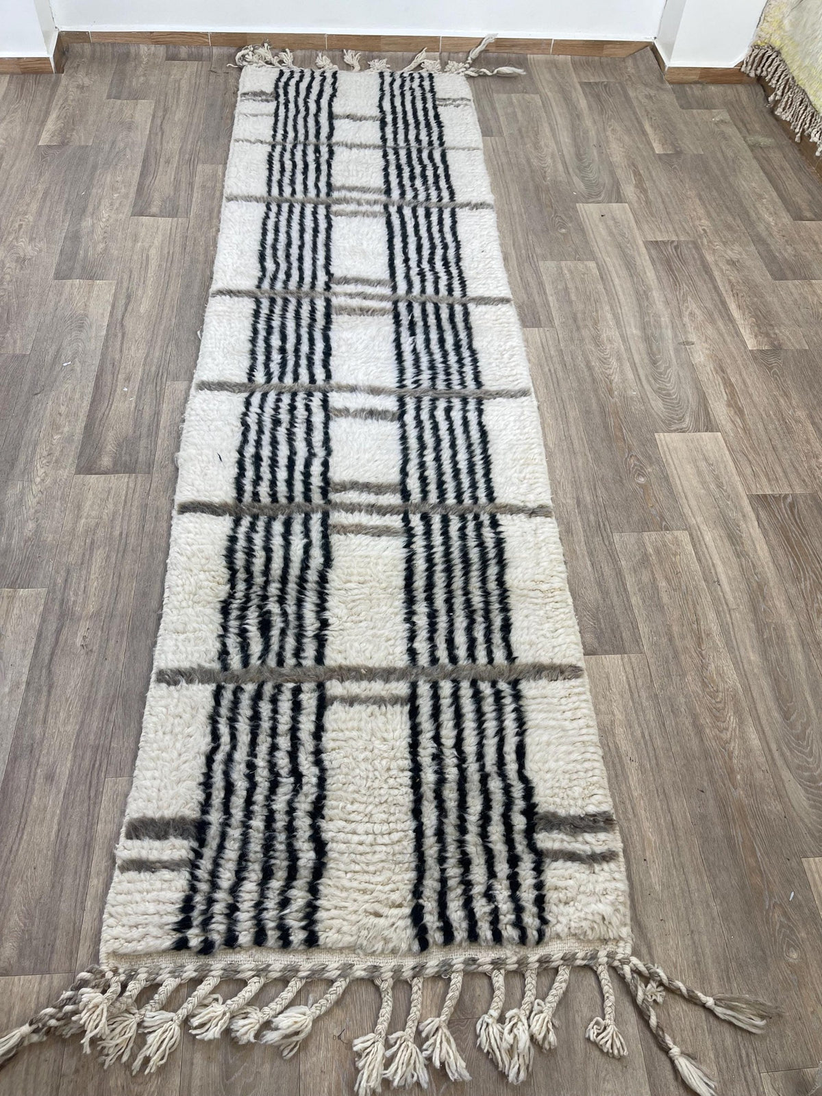 Gros plan sur les franges du tapis de couloir berbère Aknoul, écrues torsadées, nouées à la main
