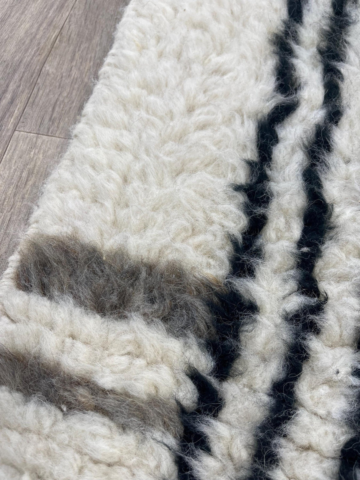 Gros plan sur la laine du tapis de couloir berbère Aknoul, laine de mouton au poil long, blanche et noire