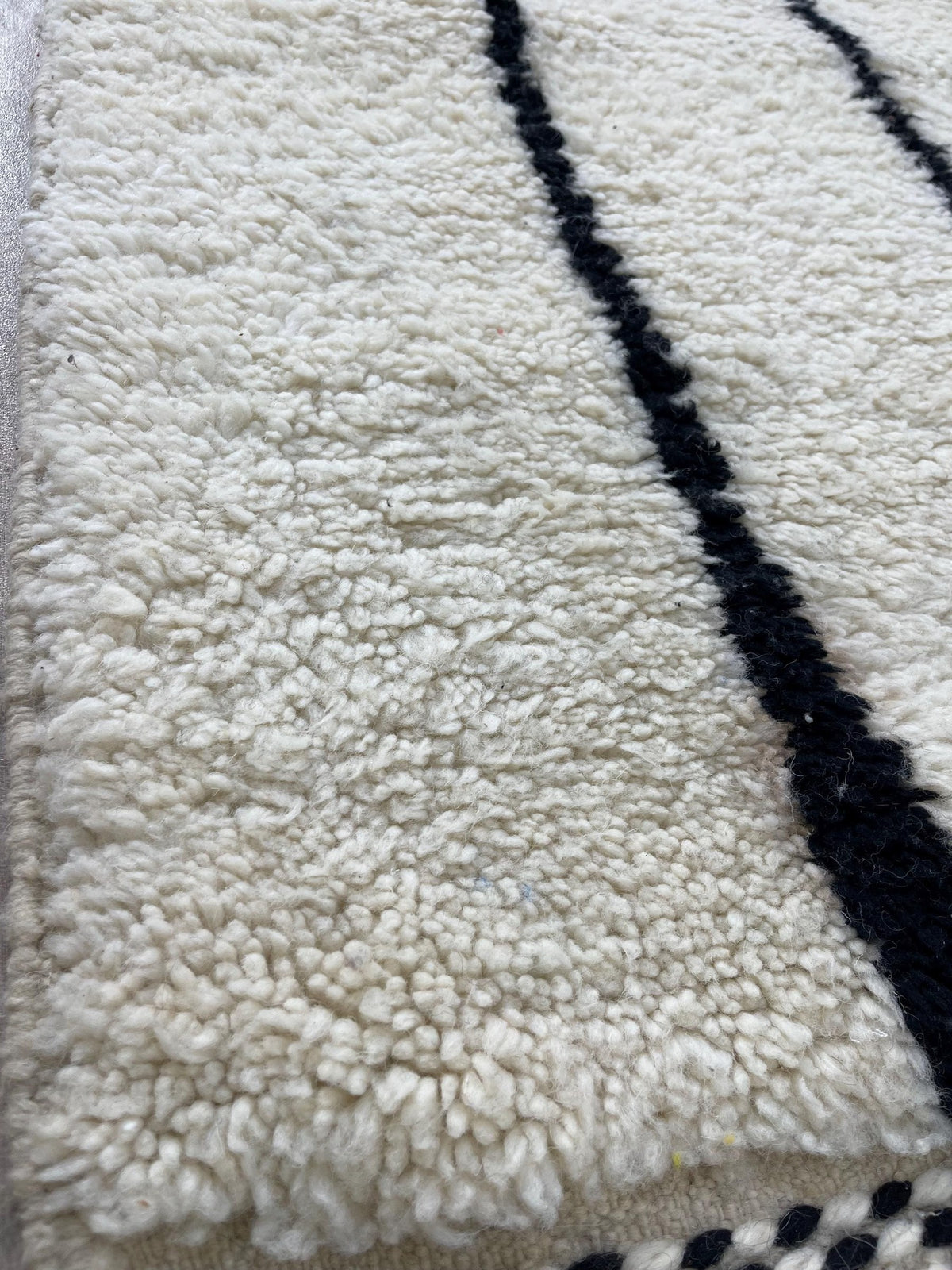 Gros plan sur la laine du tapis de couloir berbère Iberdan, laine de mouton au poil long, blanche et noire