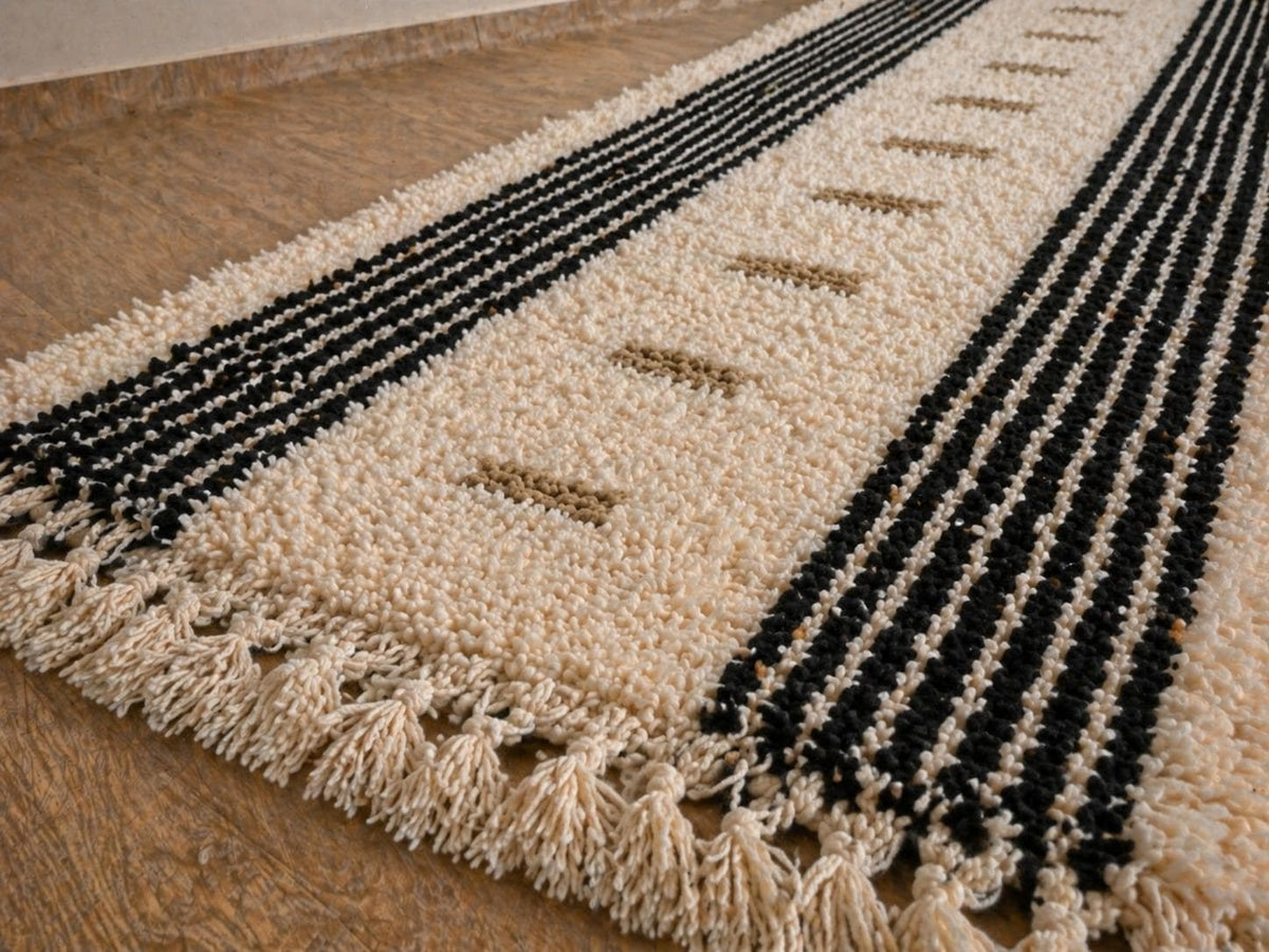 Gros plan sur les franges du tapis de couloir berbère Tallunt, écrues à pompons en bas seulement, nouées à la main