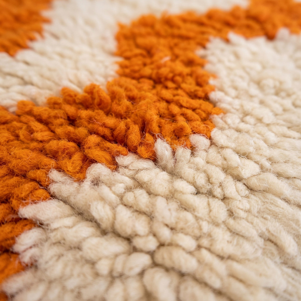 Gros plan sur un motif du tapis de couloir berbère Loumzal, couloir écru, environ huit ondulations verticales orange vif
