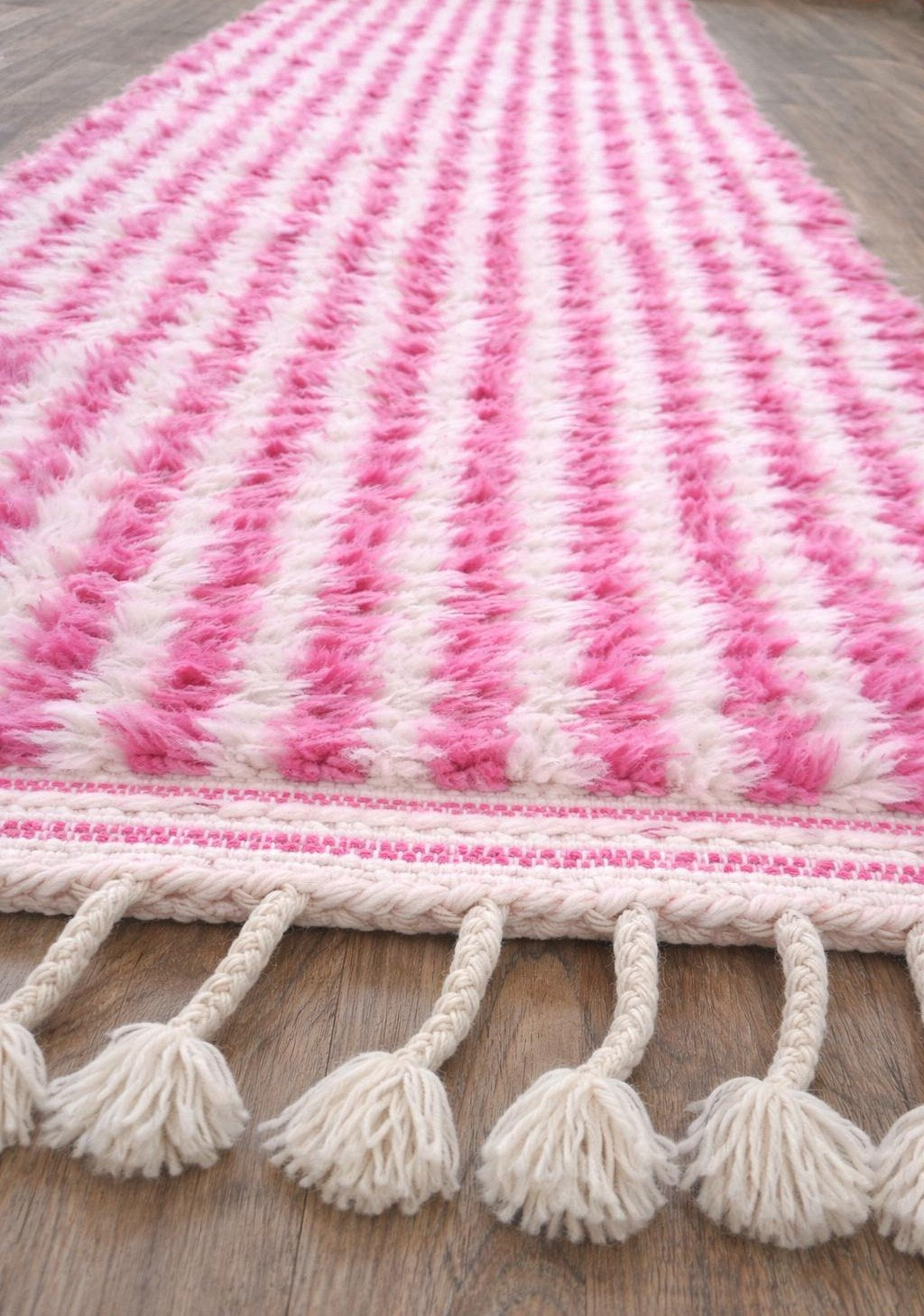 Tapis de couloir berbère à rayures rose et blanc Mirleft posé au sol vu de côté, noué main au Maroc