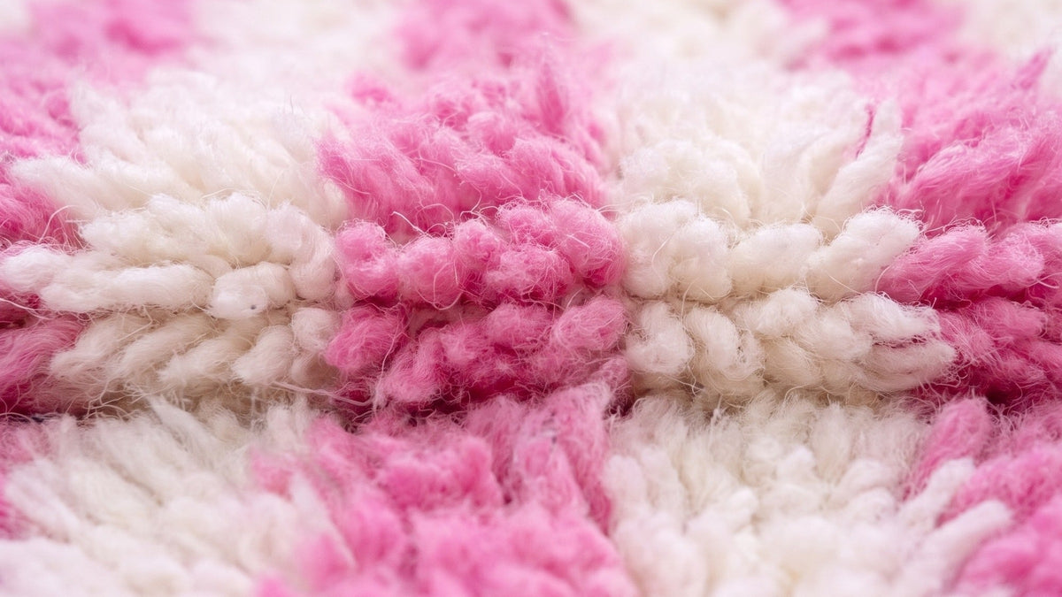 Gros plan sur la laine du tapis de couloir berbère Mirleft, poil rose et blanc noué à la main