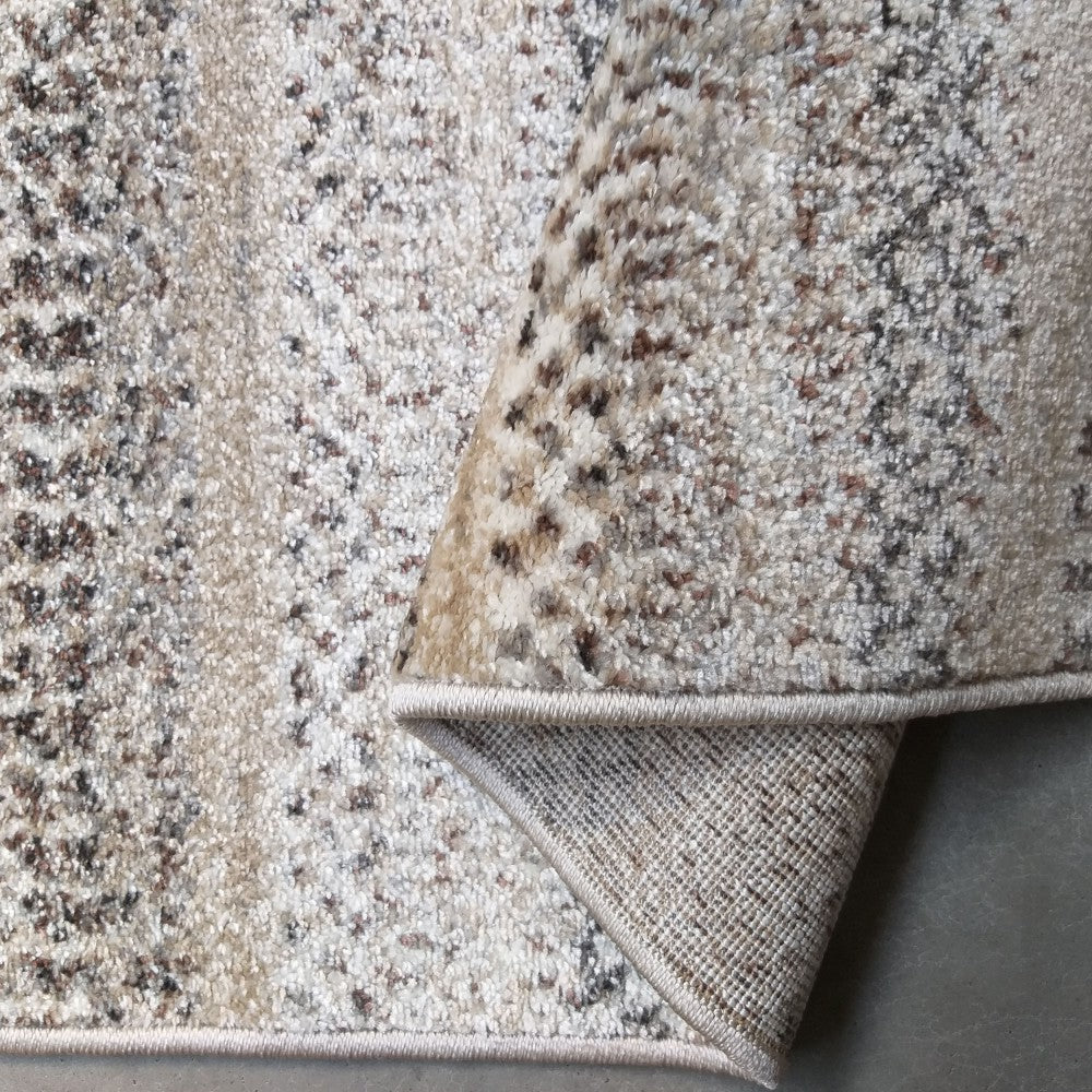 Tapis moelleux beige et crème aux motifs tachetés marron et gris, partiellement enroulé