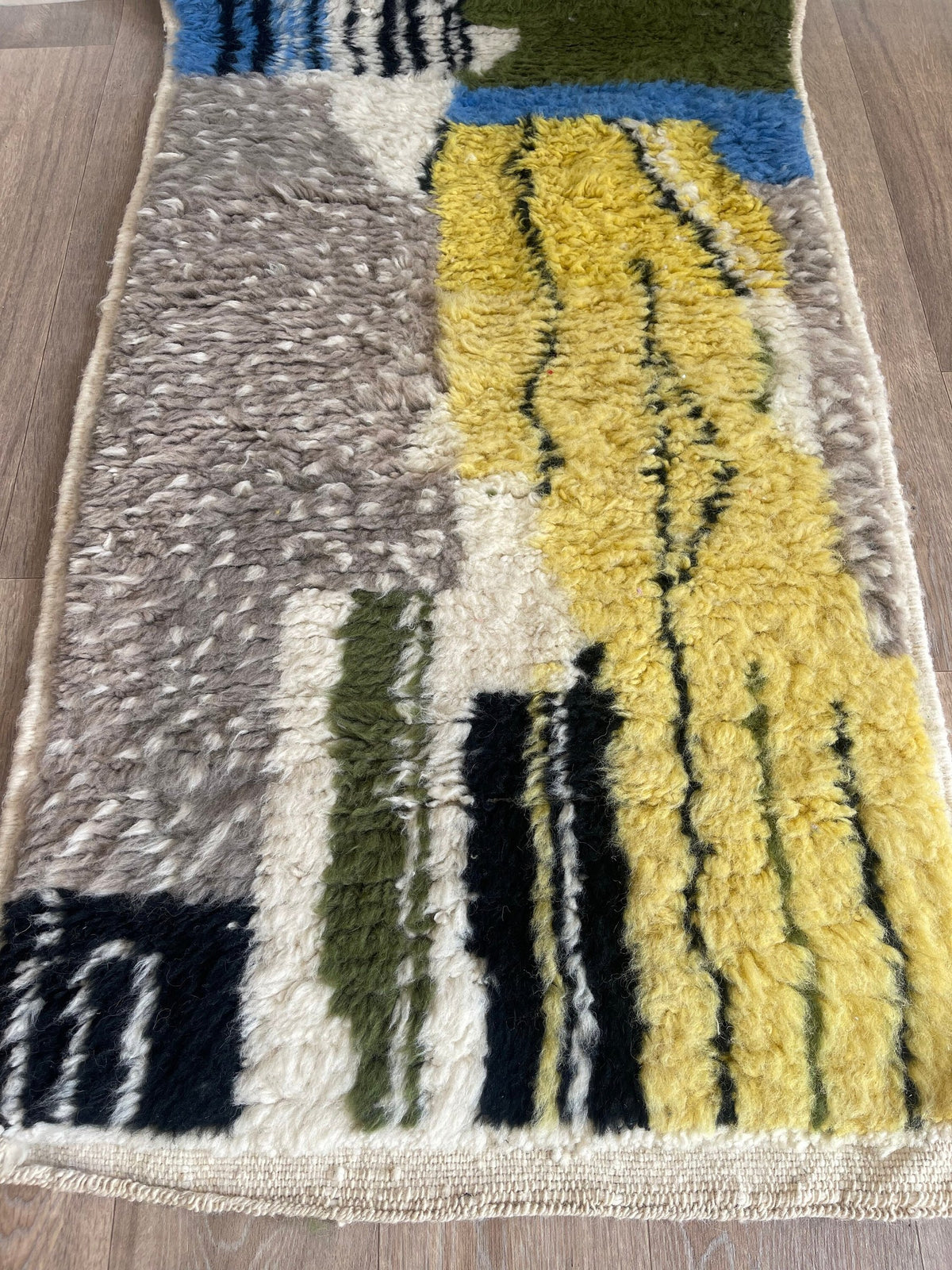 Gros plan sur un détail du tapis de couloir berbère Iznagal, poil long et motif jaune et bleu vus de près