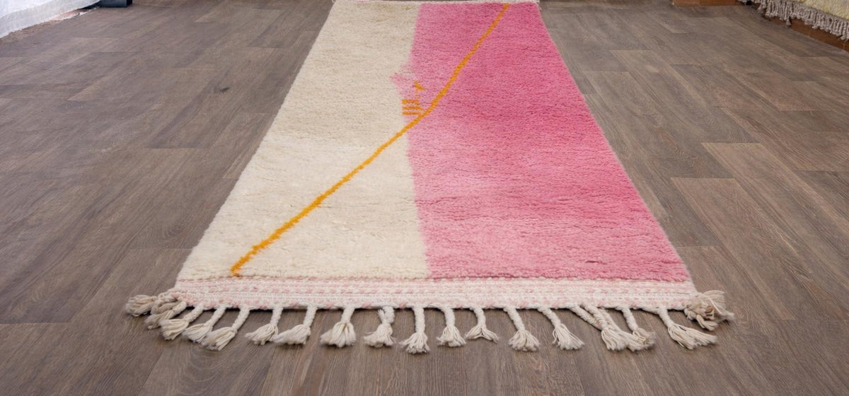 Tapis de couloir berbère coloré rose et blanc Tanmila posé au sol vu de côté, noué main au Maroc