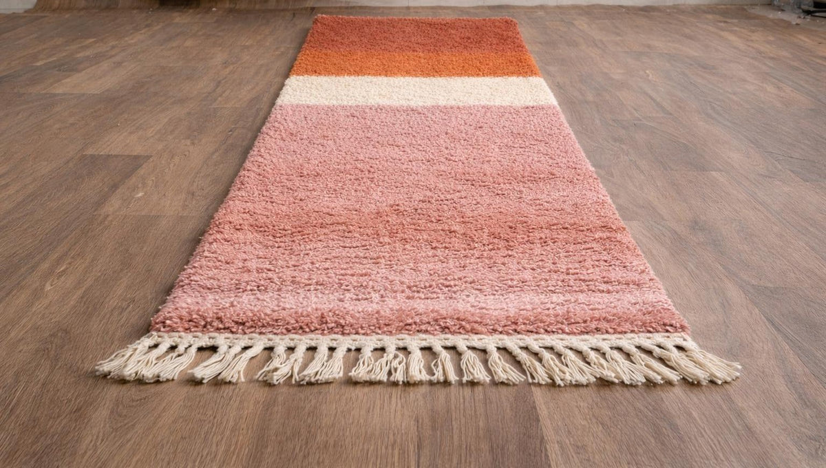 Tapis de couloir berbère coloré rose et orange Mayyu posé au sol vu de côté, noué main au Maroc