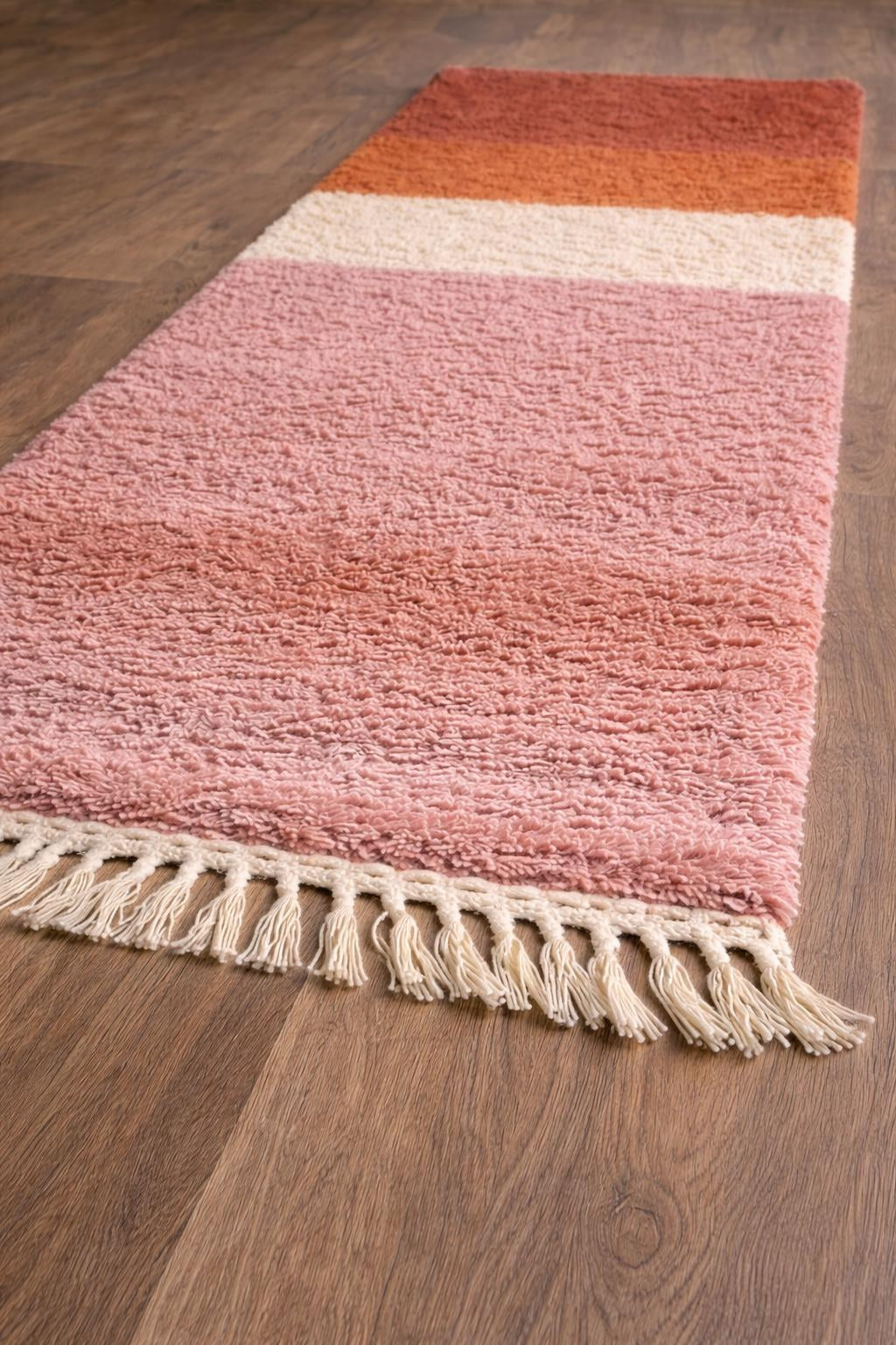 Tapis de couloir berbère coloré rose et orange Mayyu posé au sol vu de trois quarts, noué main au Maroc
