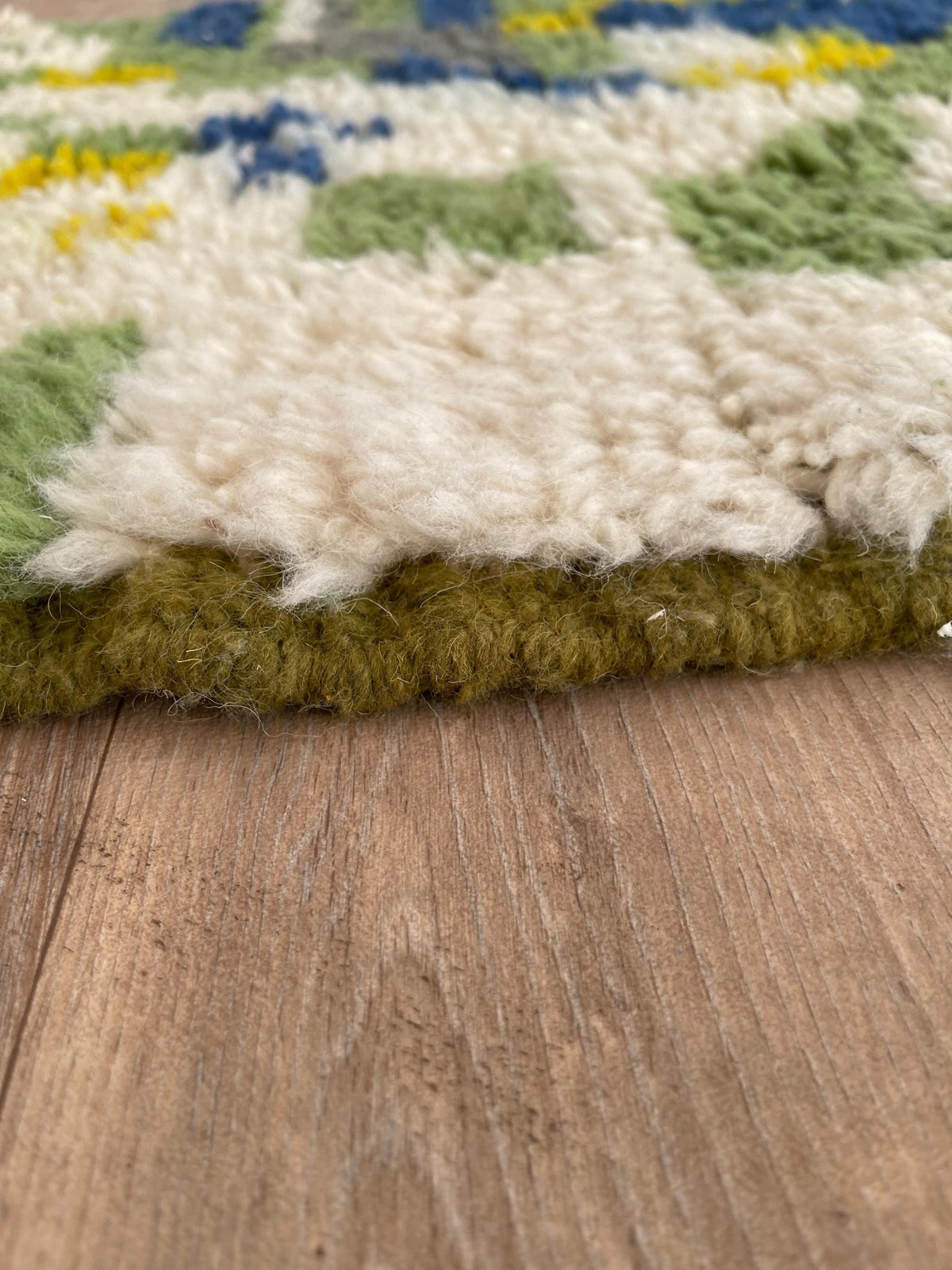 Gros plan sur le coin relevé du tapis de couloir berbère Berzoun, épaisseur du poil long et dos tissé à la main