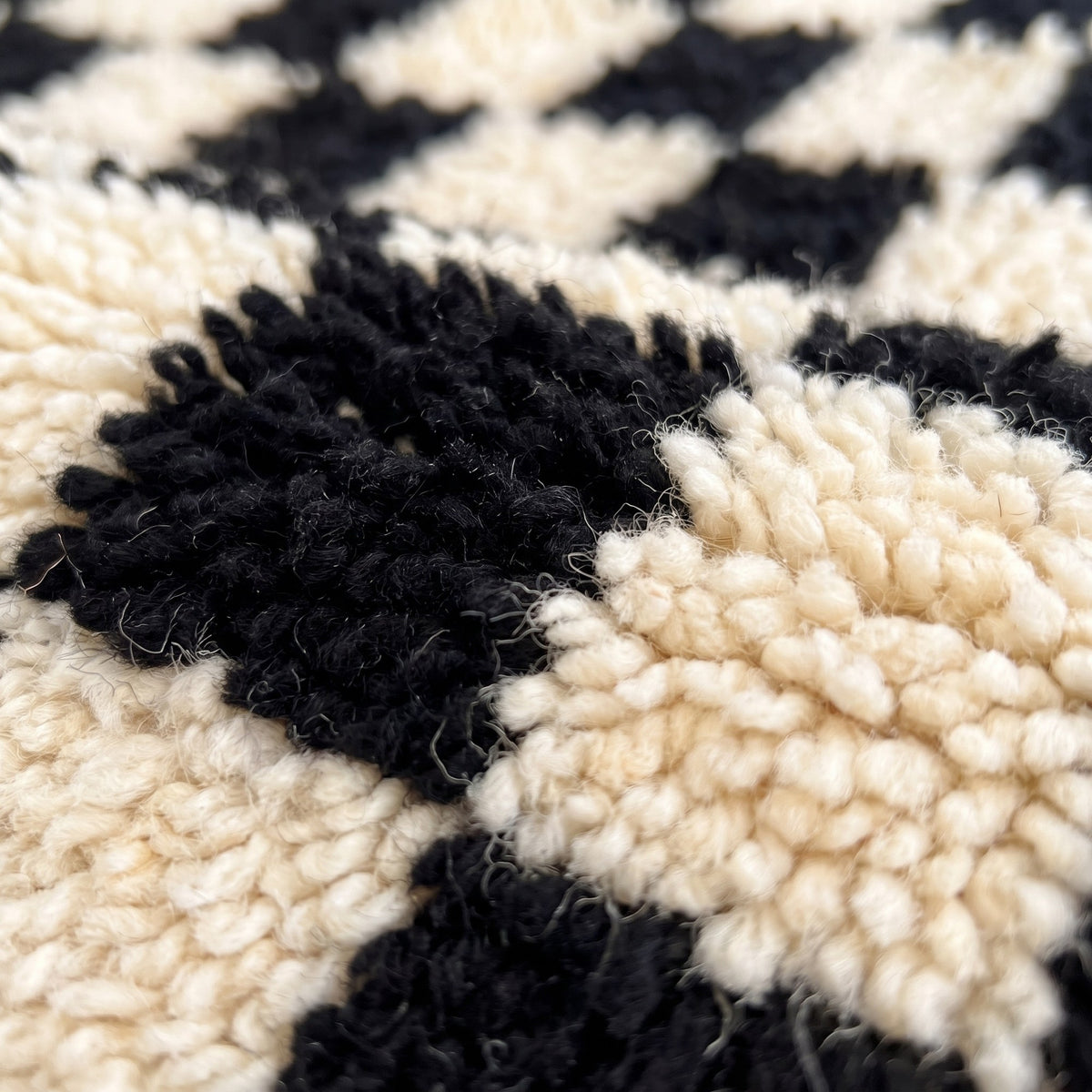 Gros plan sur un motif du tapis de couloir berbère Lemzoun, couloir à poil long en damier régulier noir