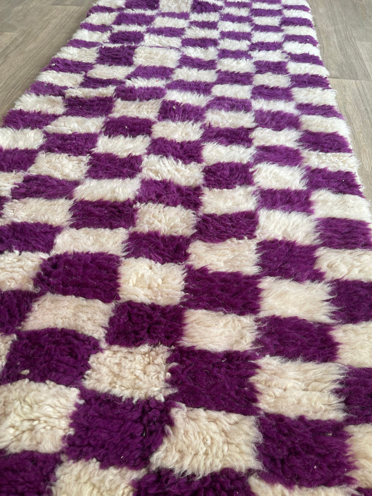 Gros plan sur un détail du tapis de couloir berbère Zerrouka, poil long et motif violet vus de près