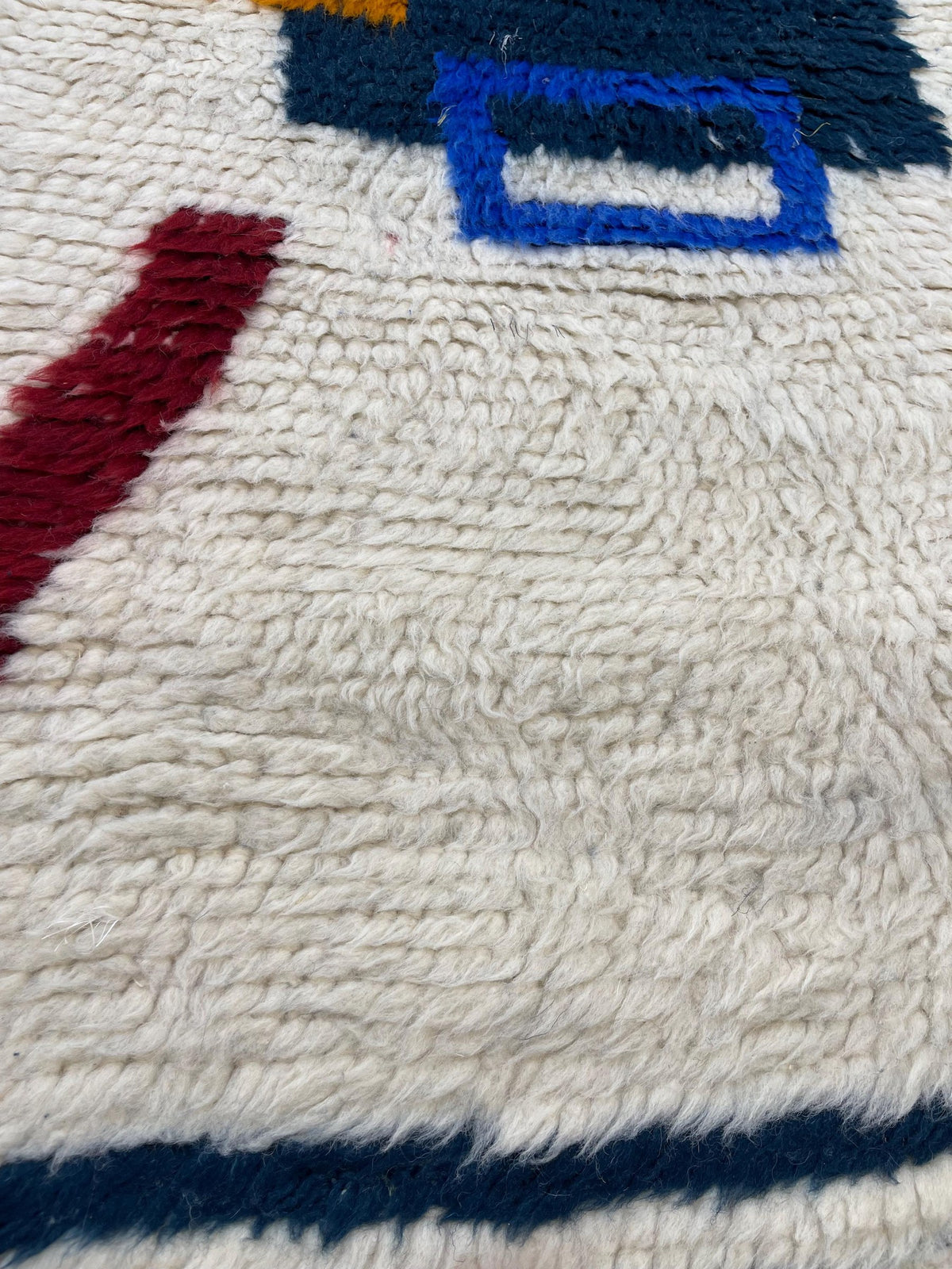 Gros plan sur la laine du tapis de couloir berbère Bouregreg, poil blanc et bleu noué à la main