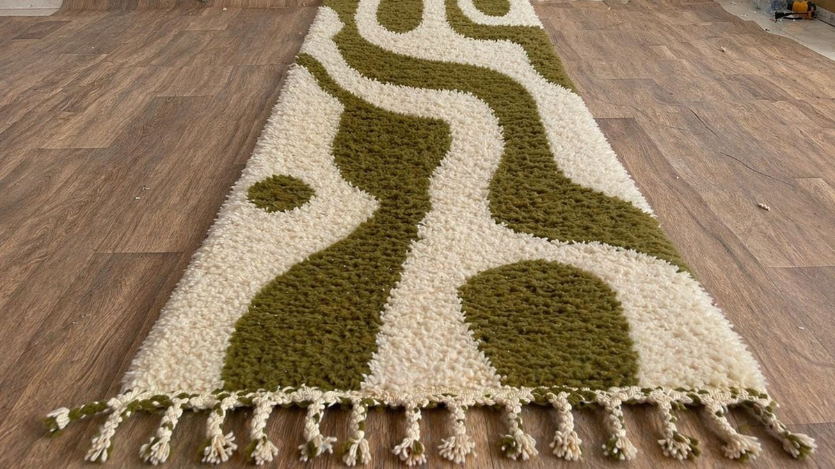 Tapis de couloir berbère graphique blanc et vert olive Assaka posé au sol vu en biais, noué main au Maroc