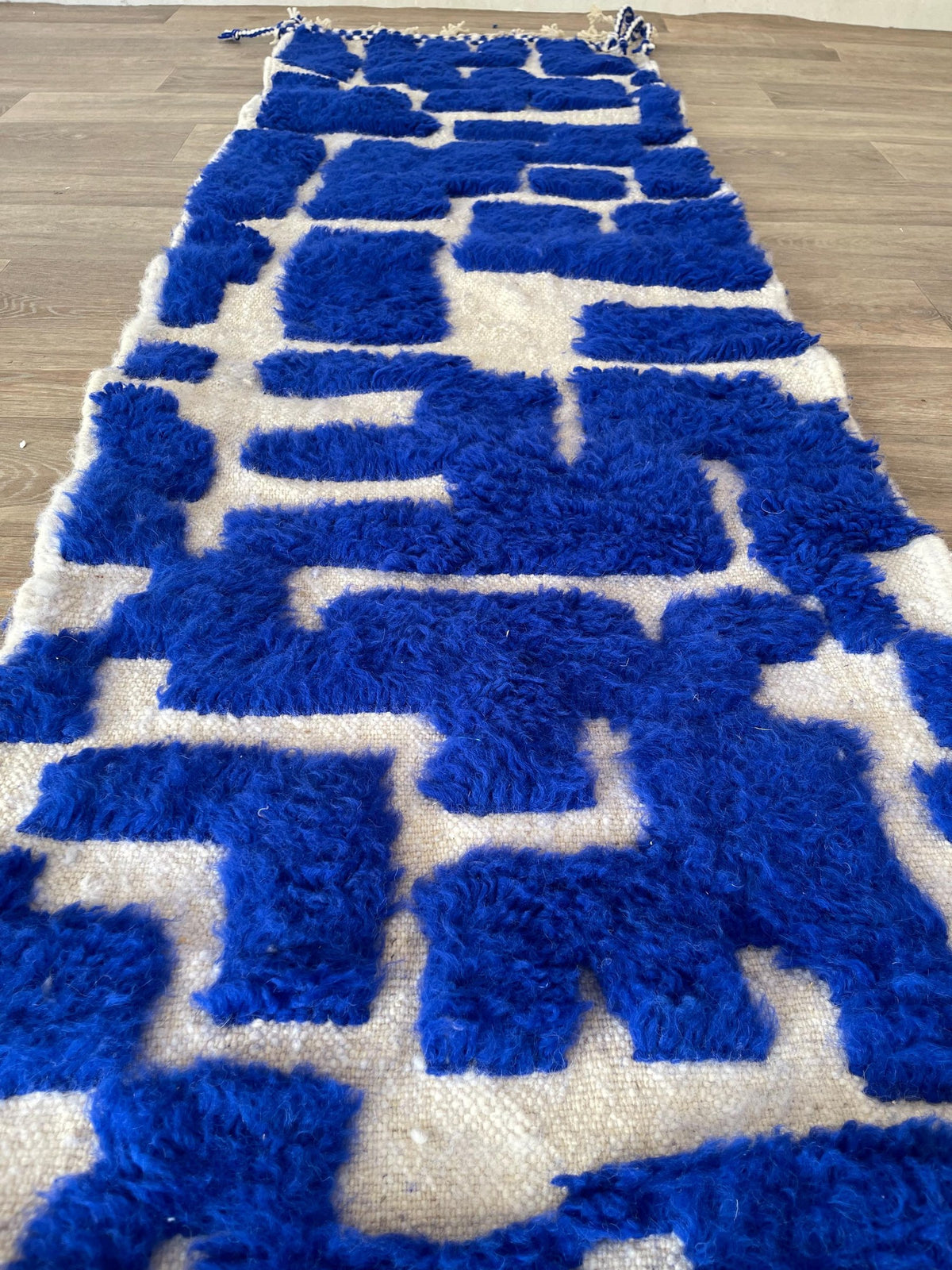 Tapis de couloir berbère graphique bleu roi Souira posé au sol vu de côté, noué main au Maroc