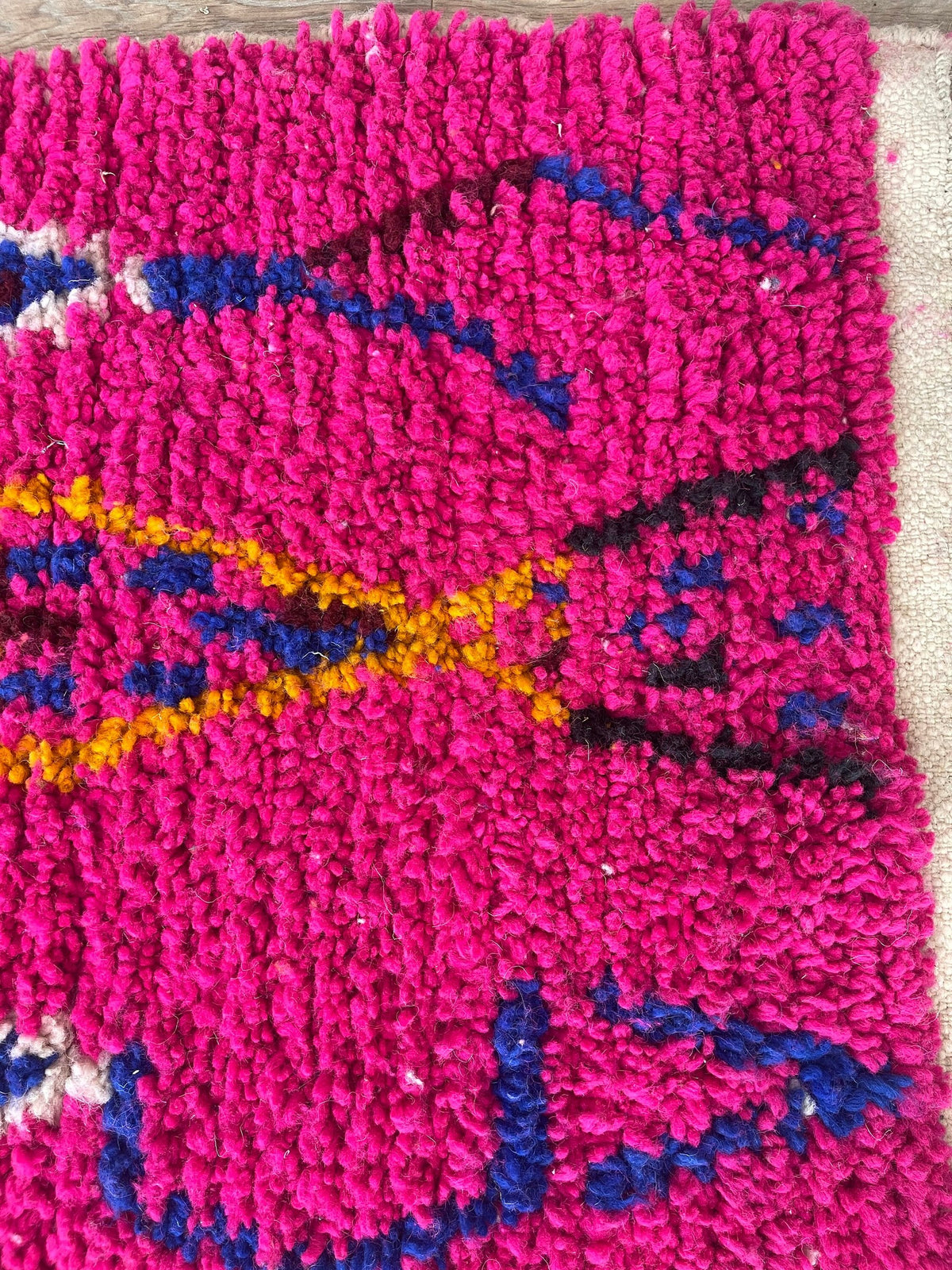 Gros plan sur le coin relevé du tapis de couloir berbère Asayis, épaisseur du poil moyen et dos tissé à la main