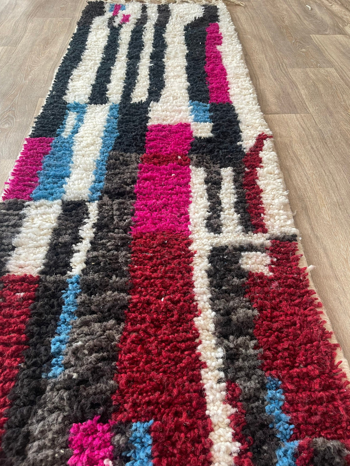 Tapis de couloir berbère graphique multicolore Belrouan posé au sol vu de côté, noué main au Maroc