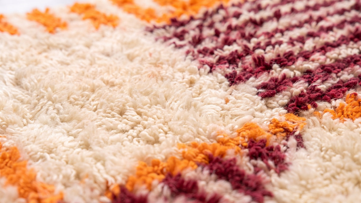 Gros plan sur la laine du tapis de couloir berbère Melgad, poil orange et bordeaux noué à la main