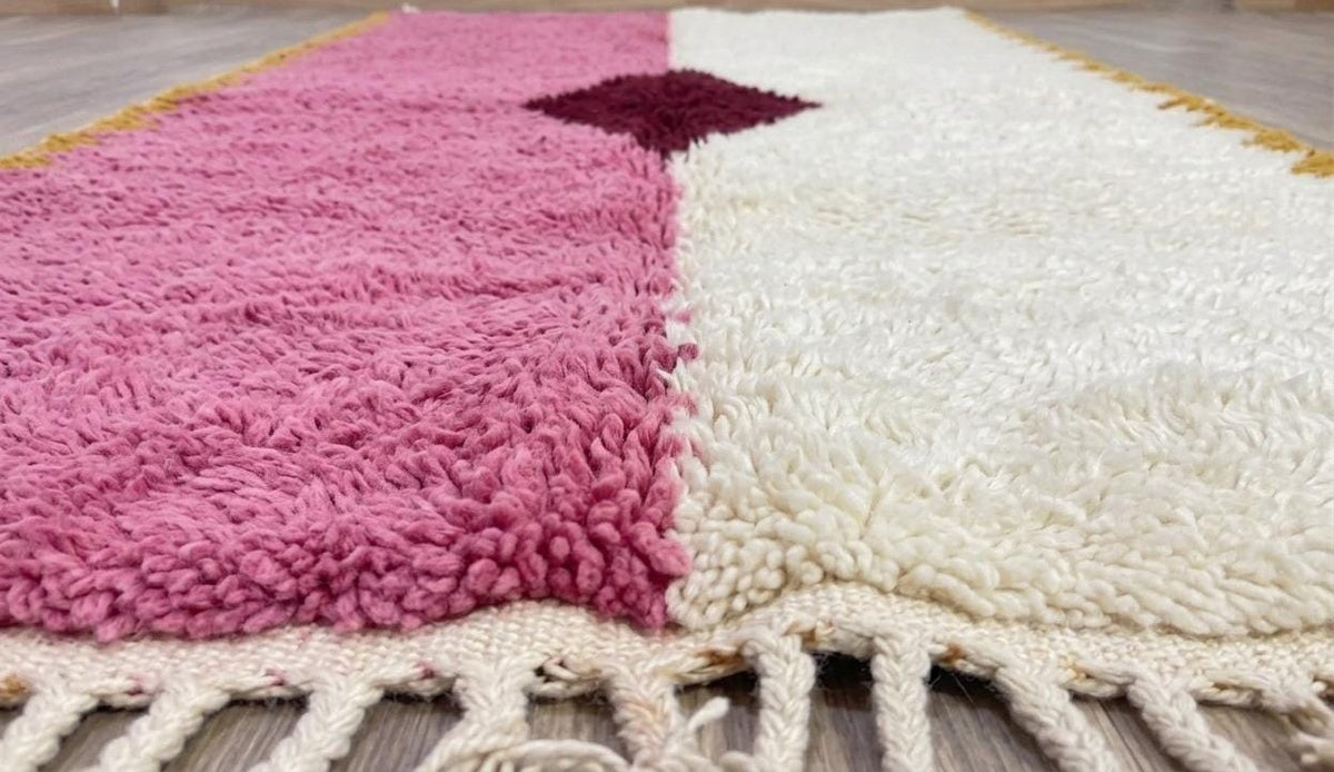 Tapis de couloir berbère graphique rose et blanc Tadsa posé au sol vu de côté, noué main au Maroc