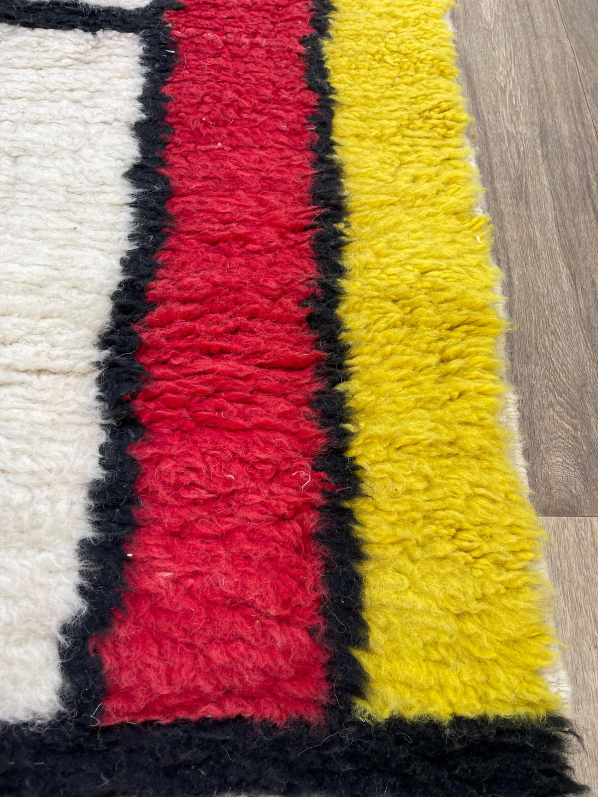 Gros plan sur la laine du tapis de couloir berbère Azetta, laine de mouton au poil long, rouge et jaune