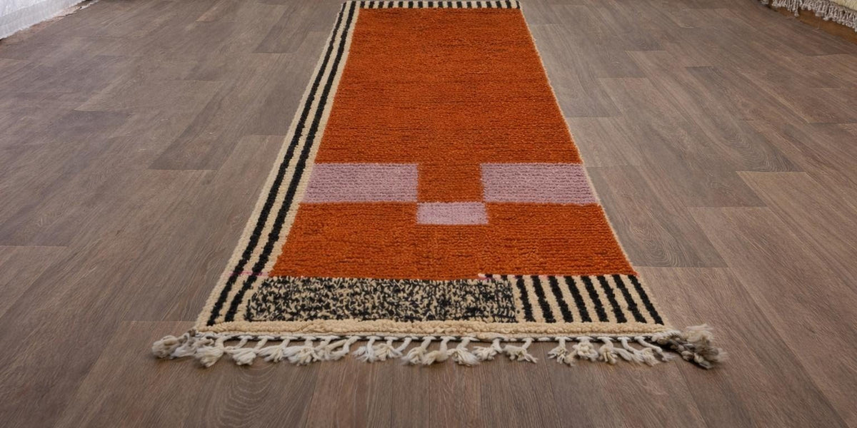 Tapis de couloir berbère graphique terracotta Boumalne posé au sol vu de côté, noué main au Maroc