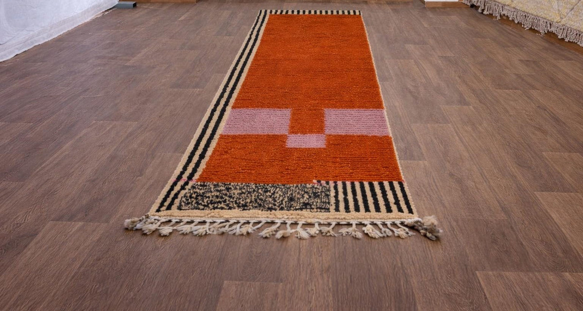 Tapis de couloir berbère graphique terracotta Boumalne posé au sol vu de trois quarts, noué main au Maroc