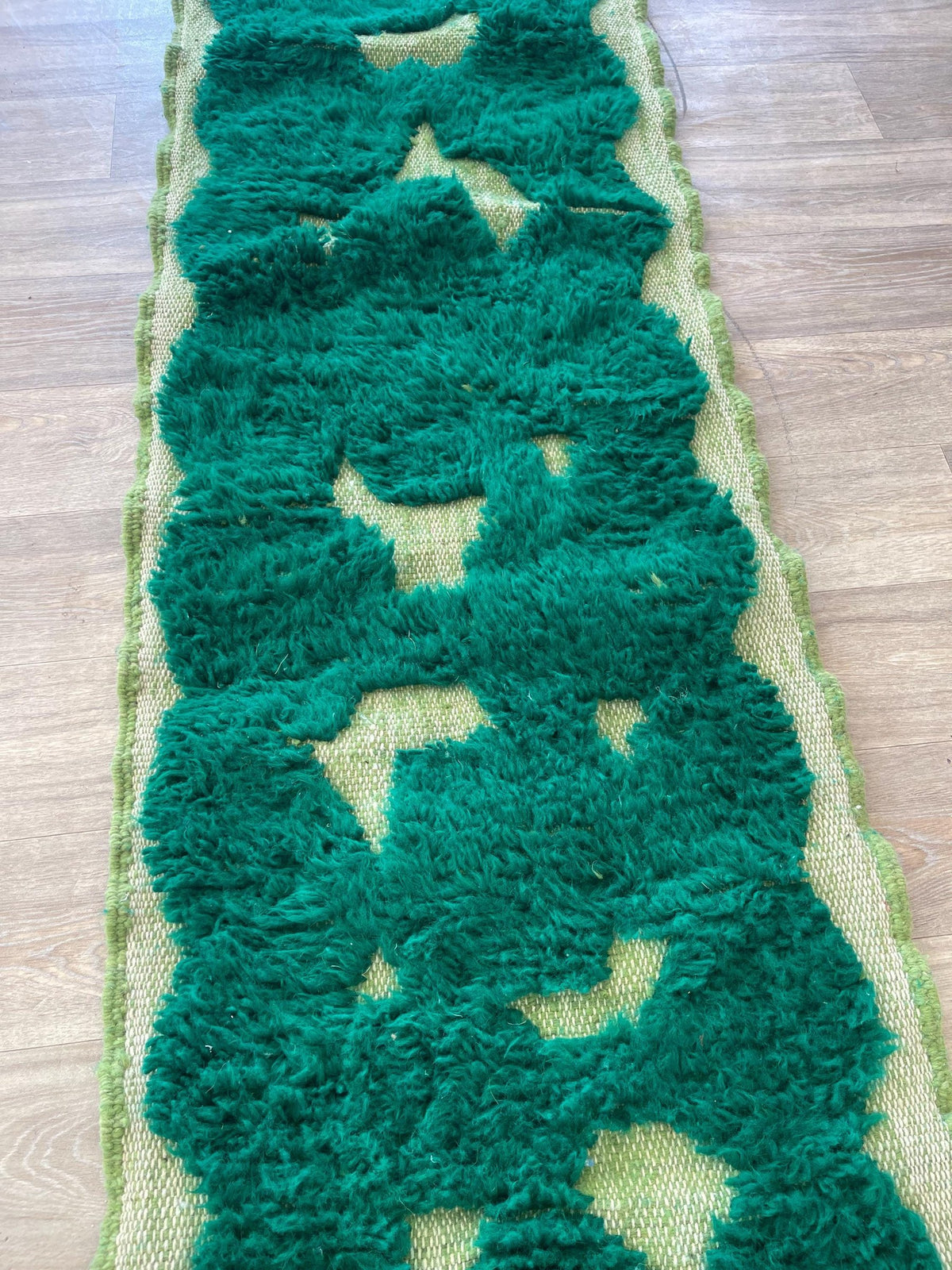 Gros plan sur un détail du tapis de couloir berbère Balissa, poil long et motif vert émeraude vus de près