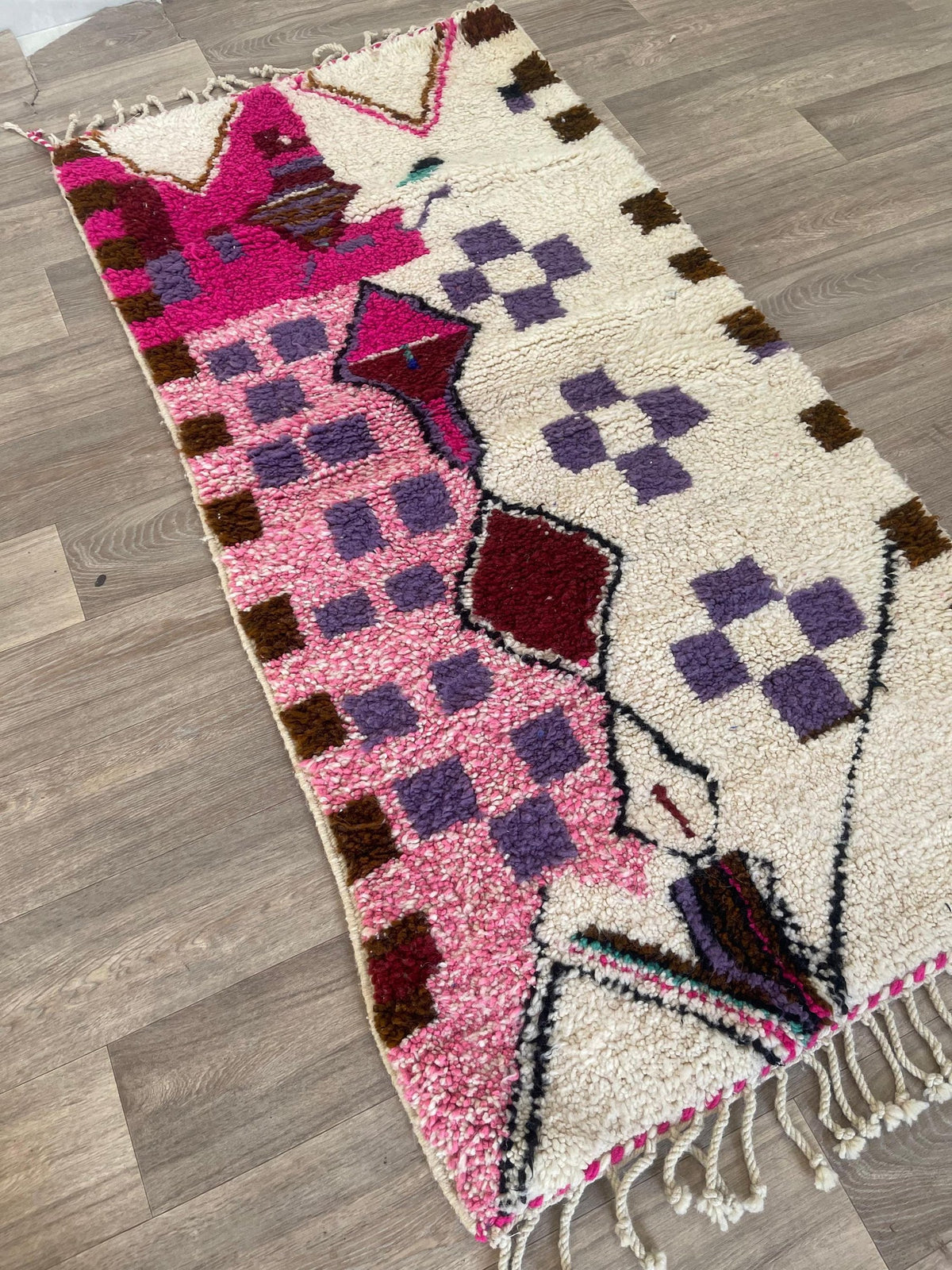 Tapis de couloir berbère style Azilal blanc et rose Zoumi posé au sol vu de côté, noué main au Maroc