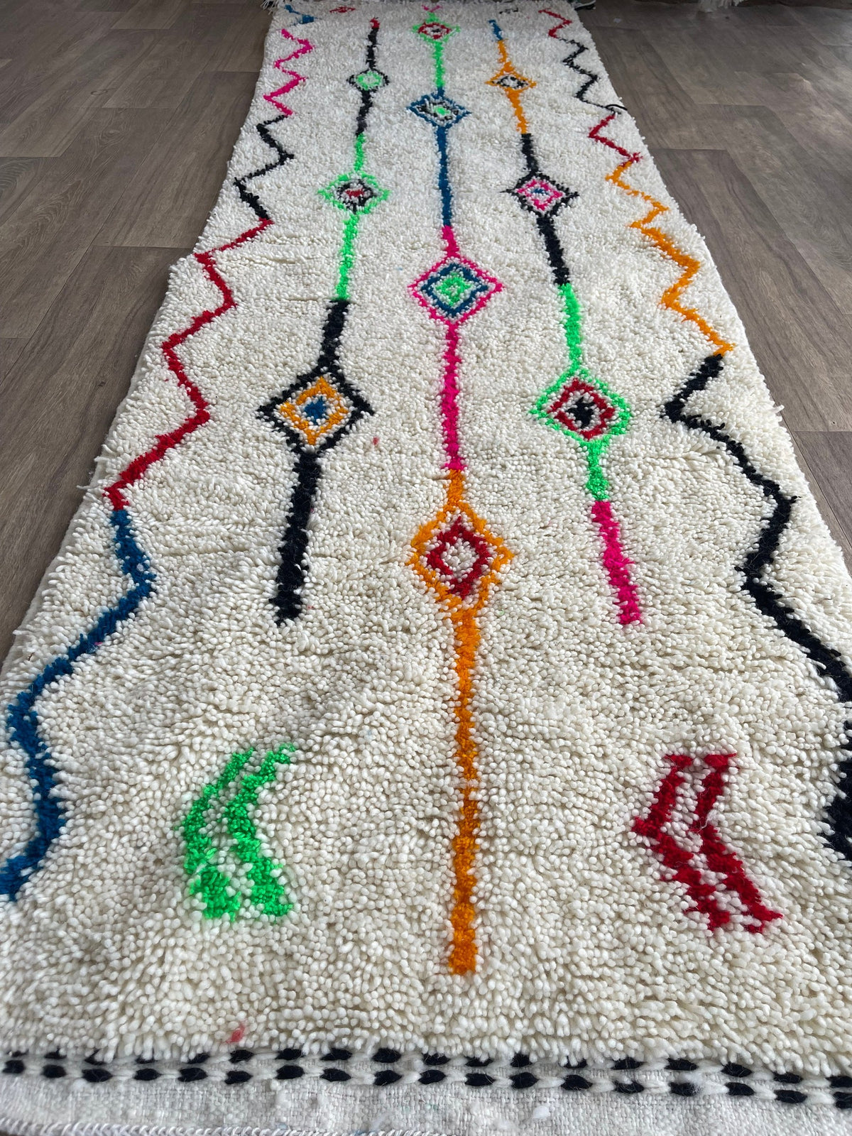 Tapis de couloir berbère style Azilal blanc multicolore Rafdil posé au sol vu de côté, noué main au Maroc