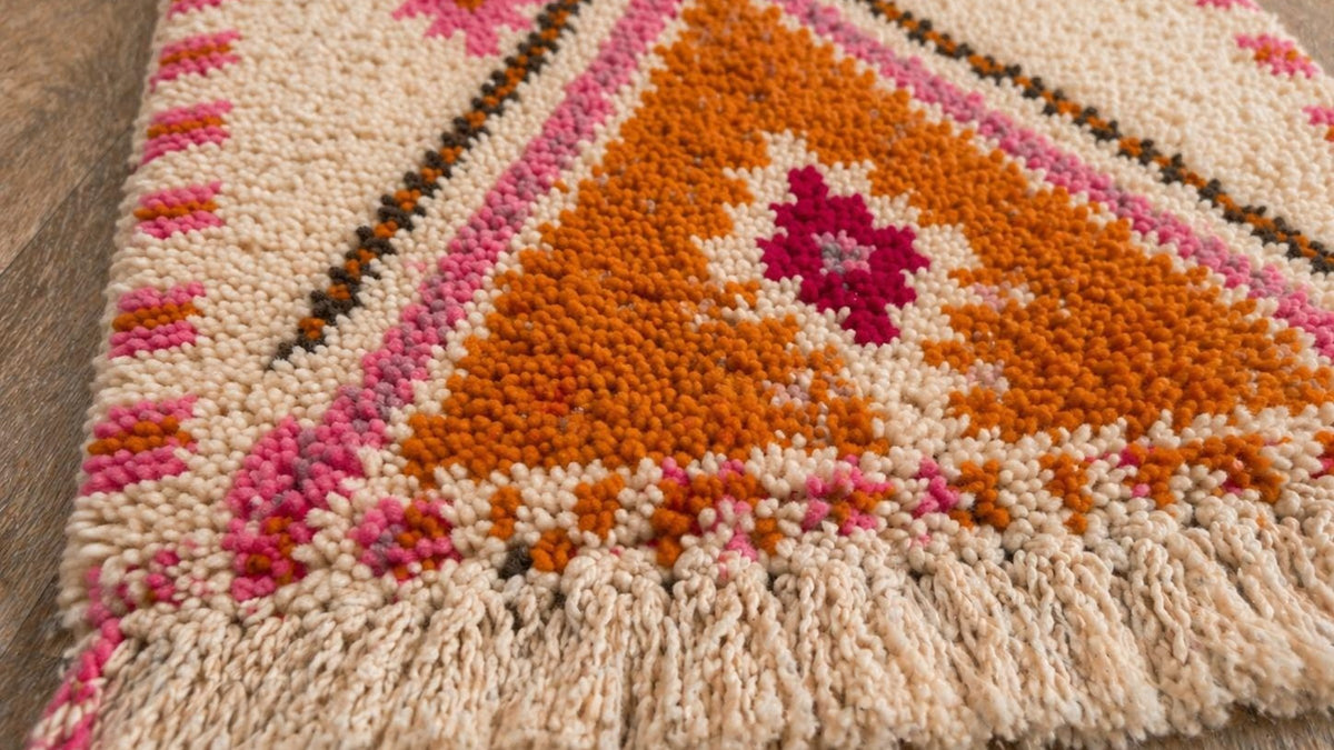 Gros plan sur la laine du tapis de couloir berbère Tifawin, poil blanc, orange et rose