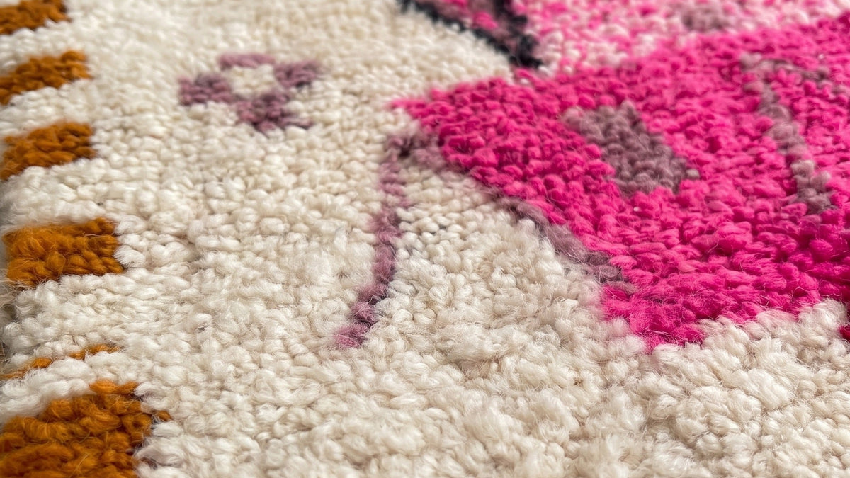 Gros plan sur la laine du tapis de couloir berbère Ameln, poil rose et blanc noué à la main