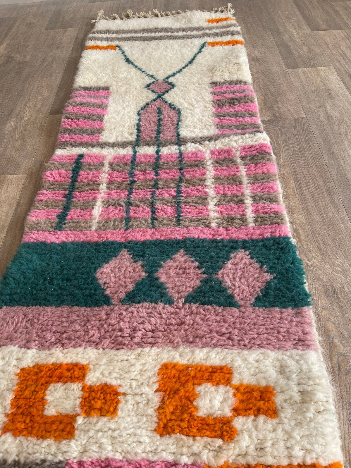 Gros plan sur un détail du tapis de couloir berbère Tikli, poil long et motif rose et orange vus de près
