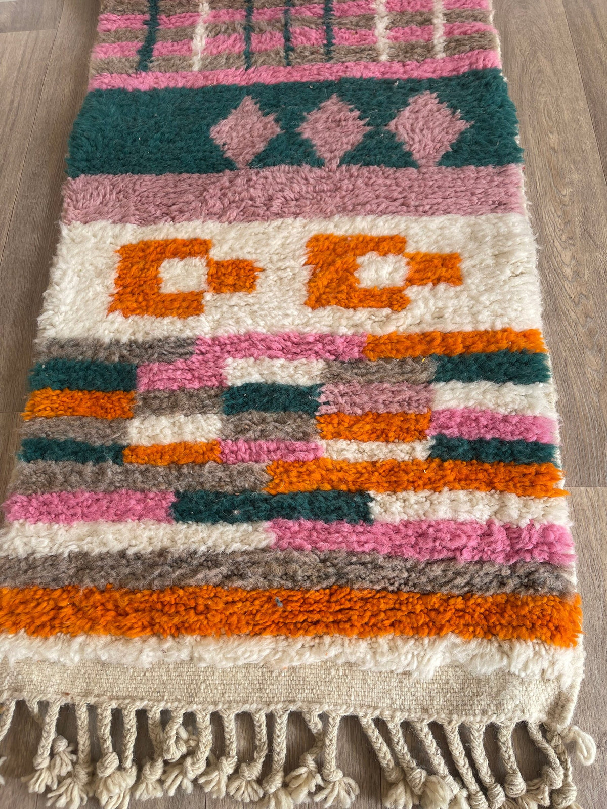 Gros plan sur la laine du tapis de couloir berbère Tikli, poil rose et orange noué à la main