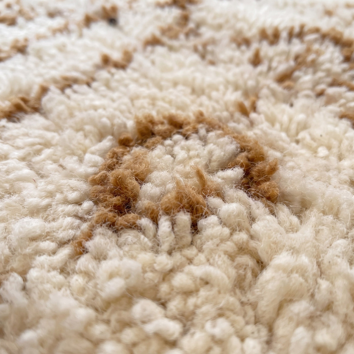 Gros plan sur un motif du tapis de couloir berbère Zemroun, couloir écru à poil long, motifs caramel