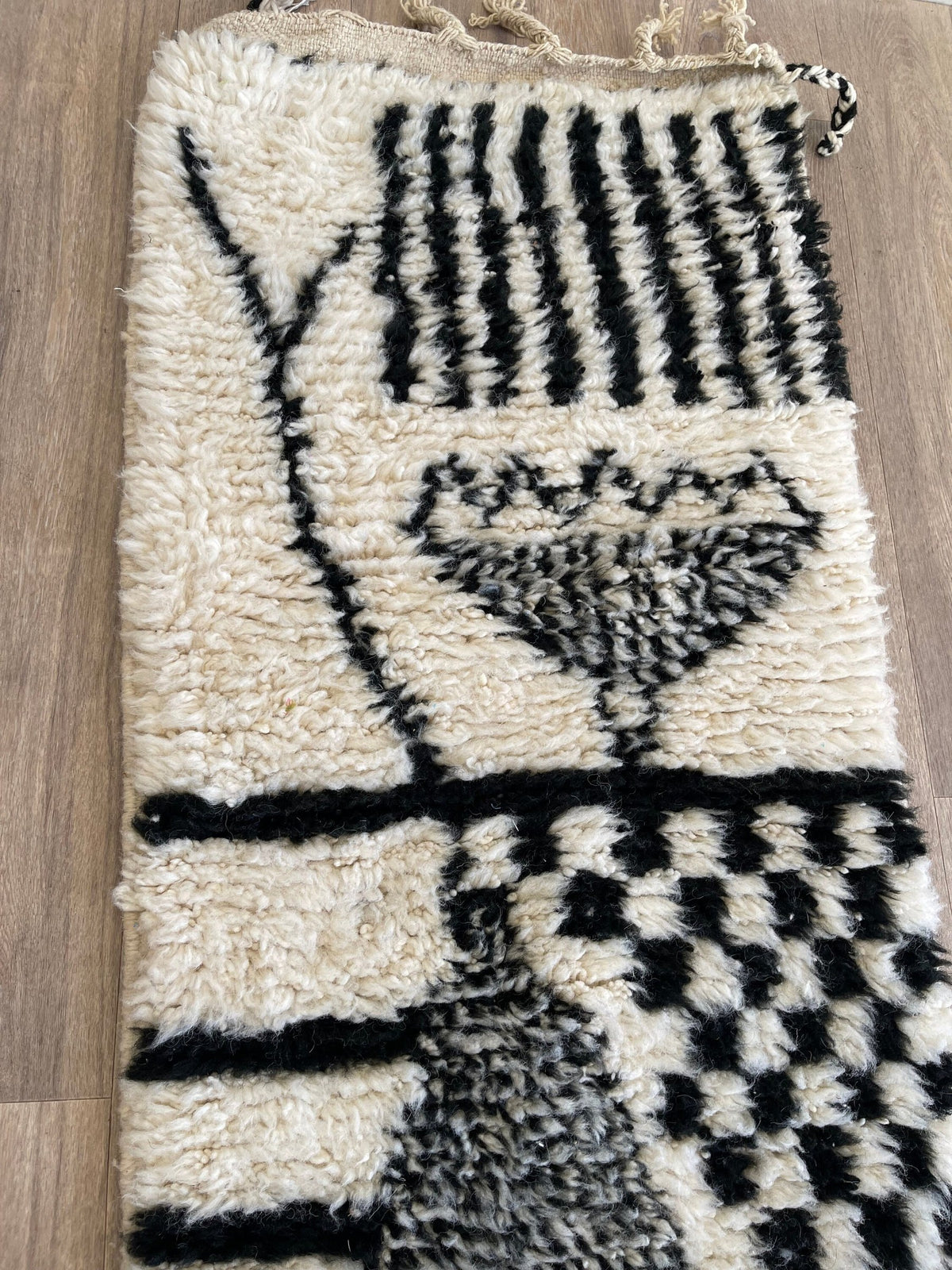 Gros plan sur un détail du tapis de couloir berbère Chellah, poil long et motif blanc et noir vus de près