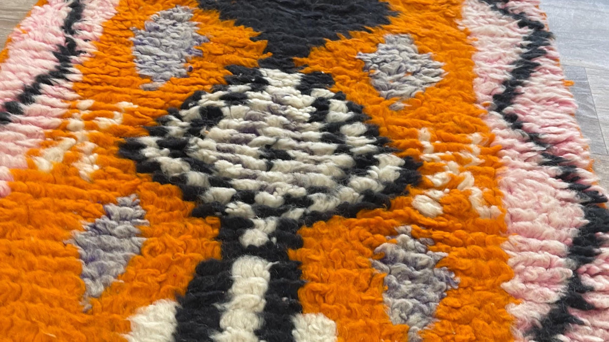 Gros plan sur la laine du tapis de couloir berbère Khamlia, poil orange et rose noué à la main