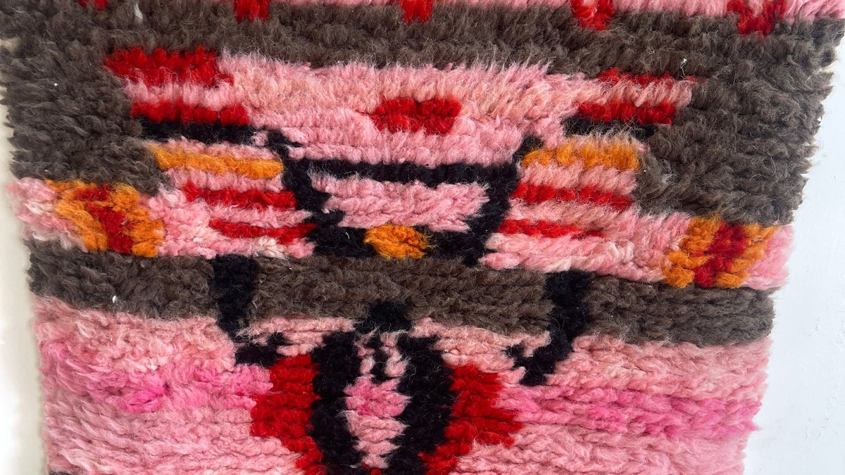 Gros plan sur la laine du tapis de couloir berbère Imilchil, poil rose et rouge noué à la main