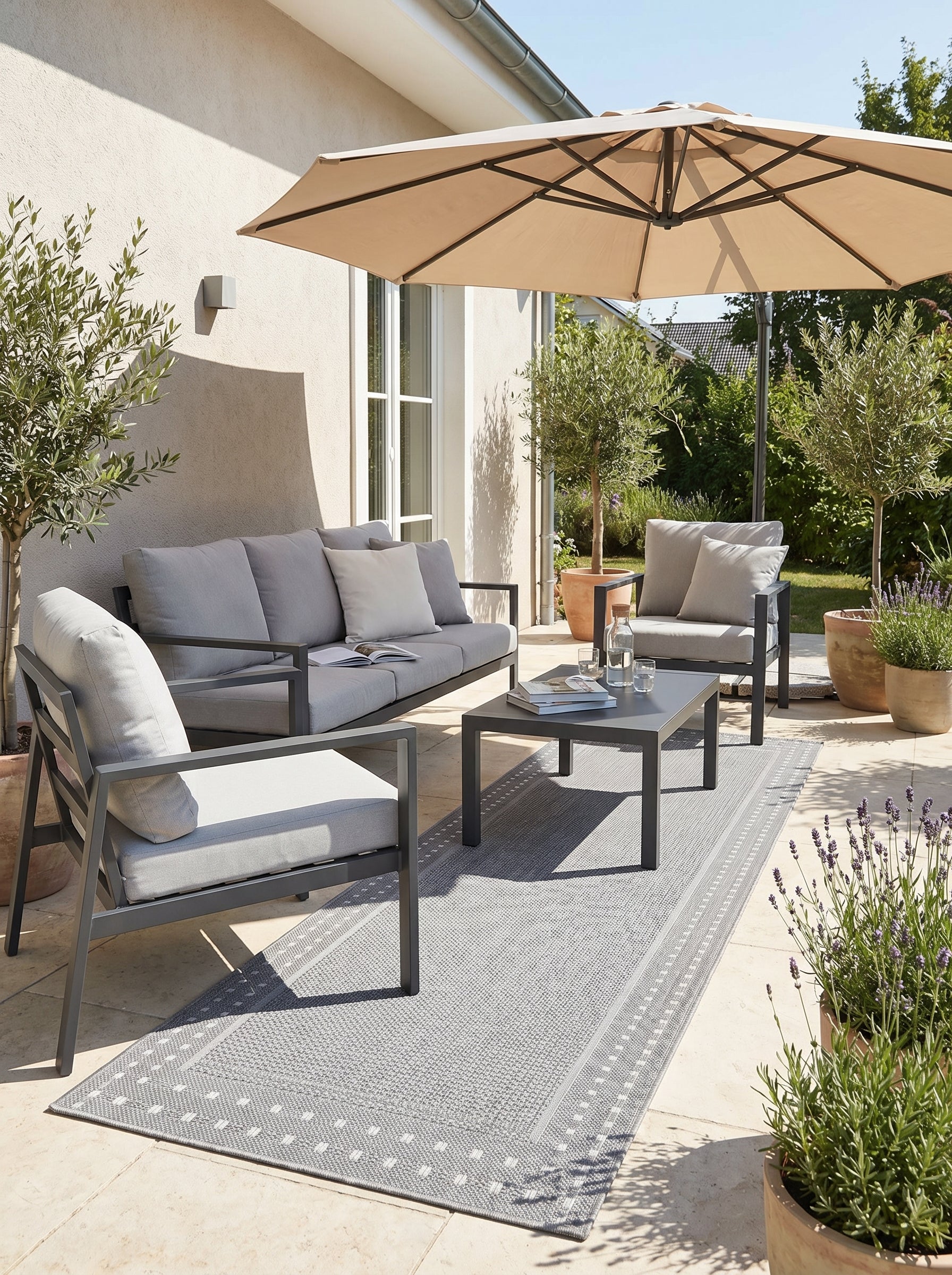 Tapis rectangulaire tissé gris clair avec une bordure à motifs de points blancs, sur une terrasse extérieure