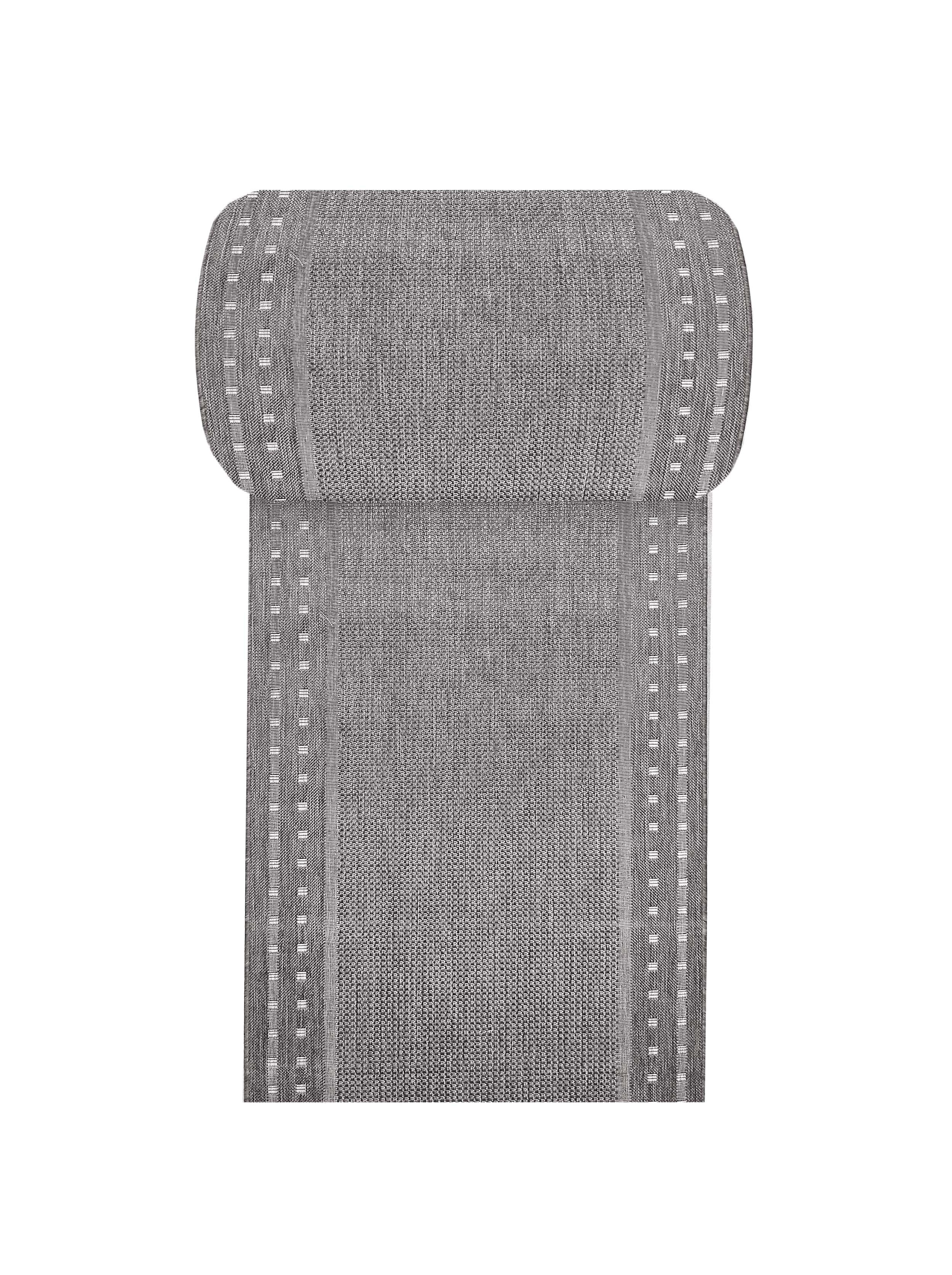 Tapis gris texturé avec un motif de bandes verticales et de petits rectangles blancs sur les bords, le haut est roulé