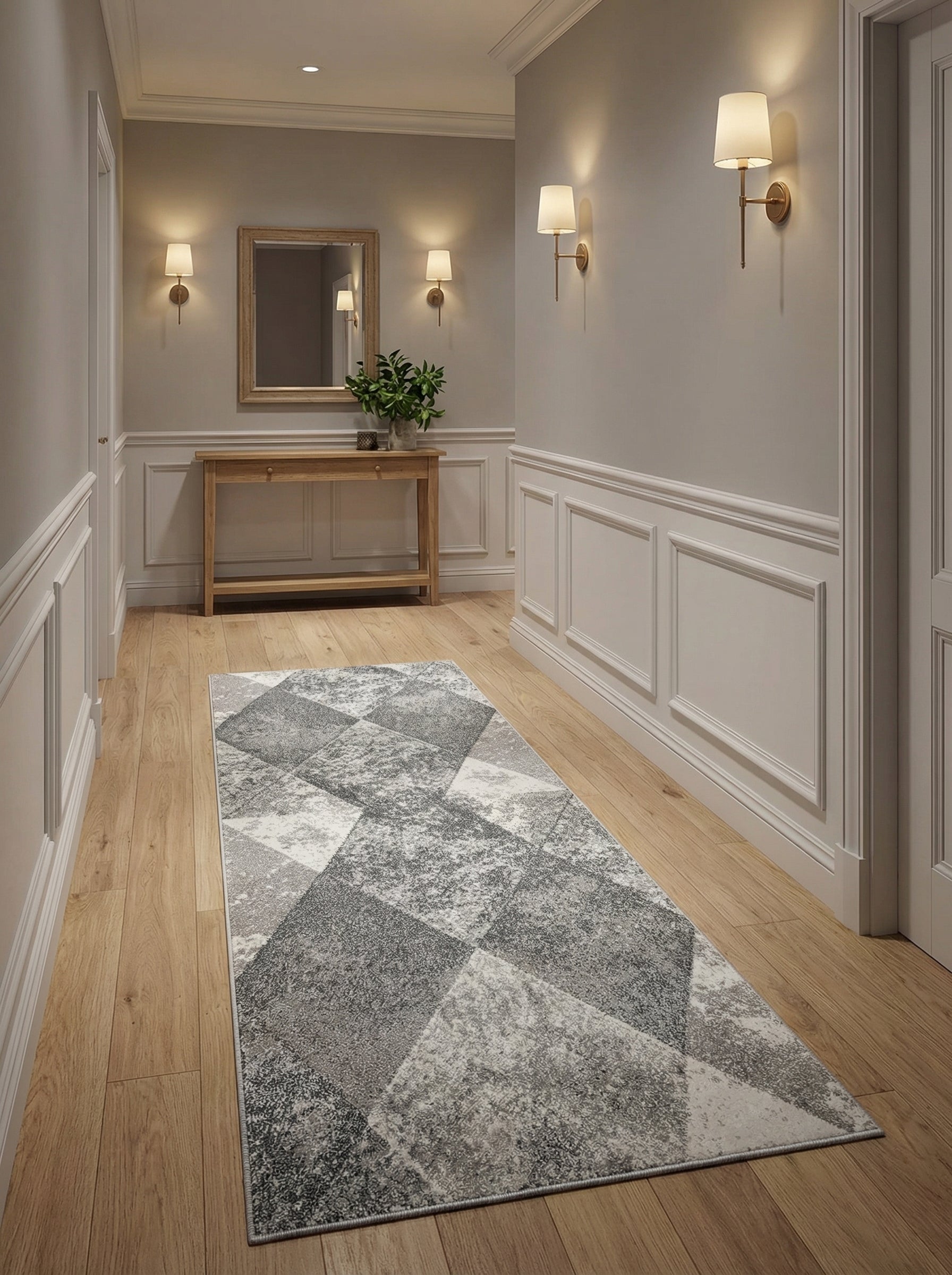 Tapis rectangulaire à motifs géométriques gris clairs et foncés, et blanc, sur un parquet clair dans un couloir