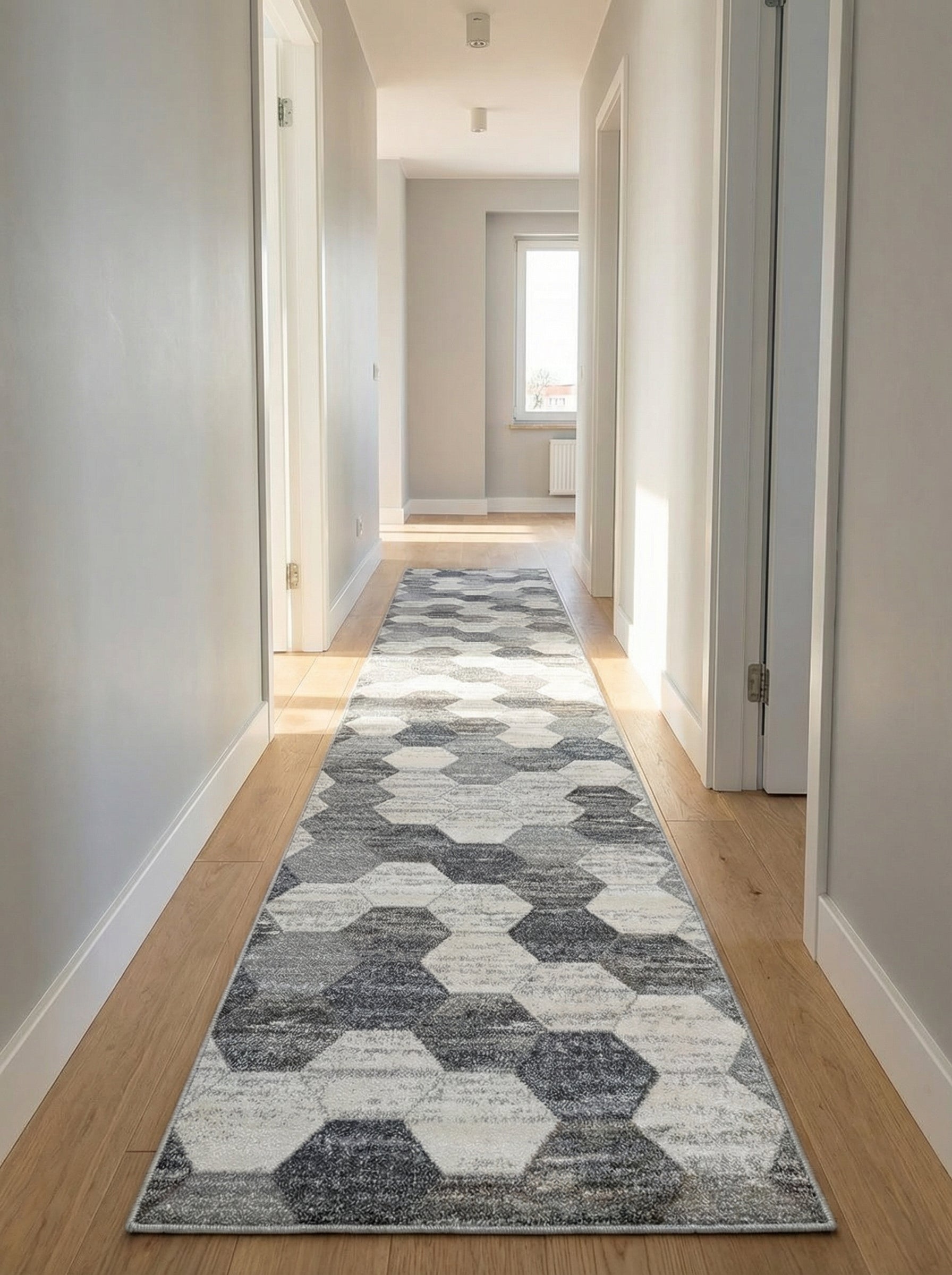 Tapis de couloir à motifs hexagonaux dégradés de gris et blanc, sur un parquet clair dans un couloir moderne