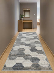 Tapis long aux motifs hexagonaux gris, anthracite et blanc cassé sur un sol en parquet clair dans un couloir moderne