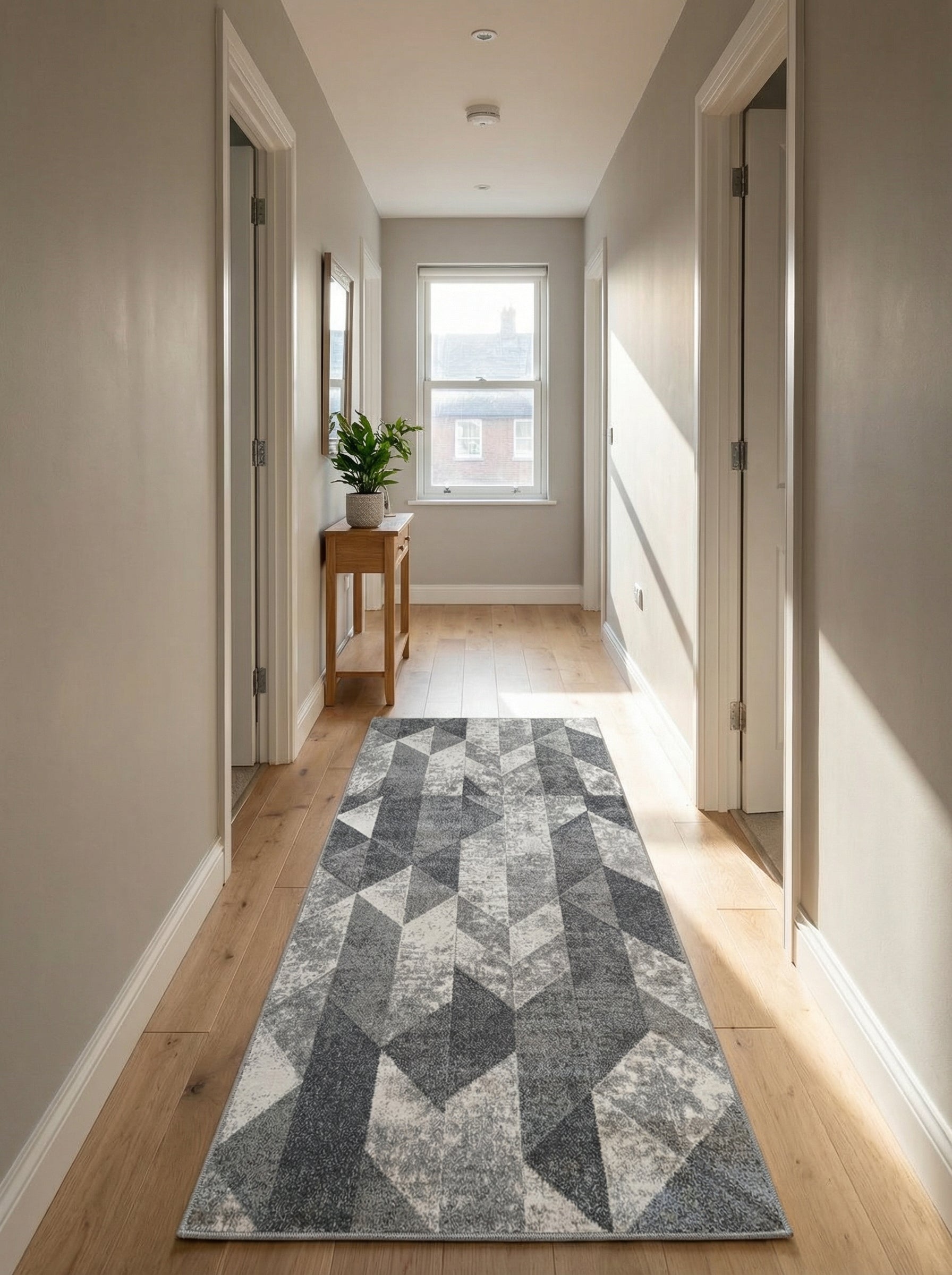 Tapis de couloir rectangulaire aux motifs géométriques en dégradés de gris et blanc, sur parquet dans un couloir clair