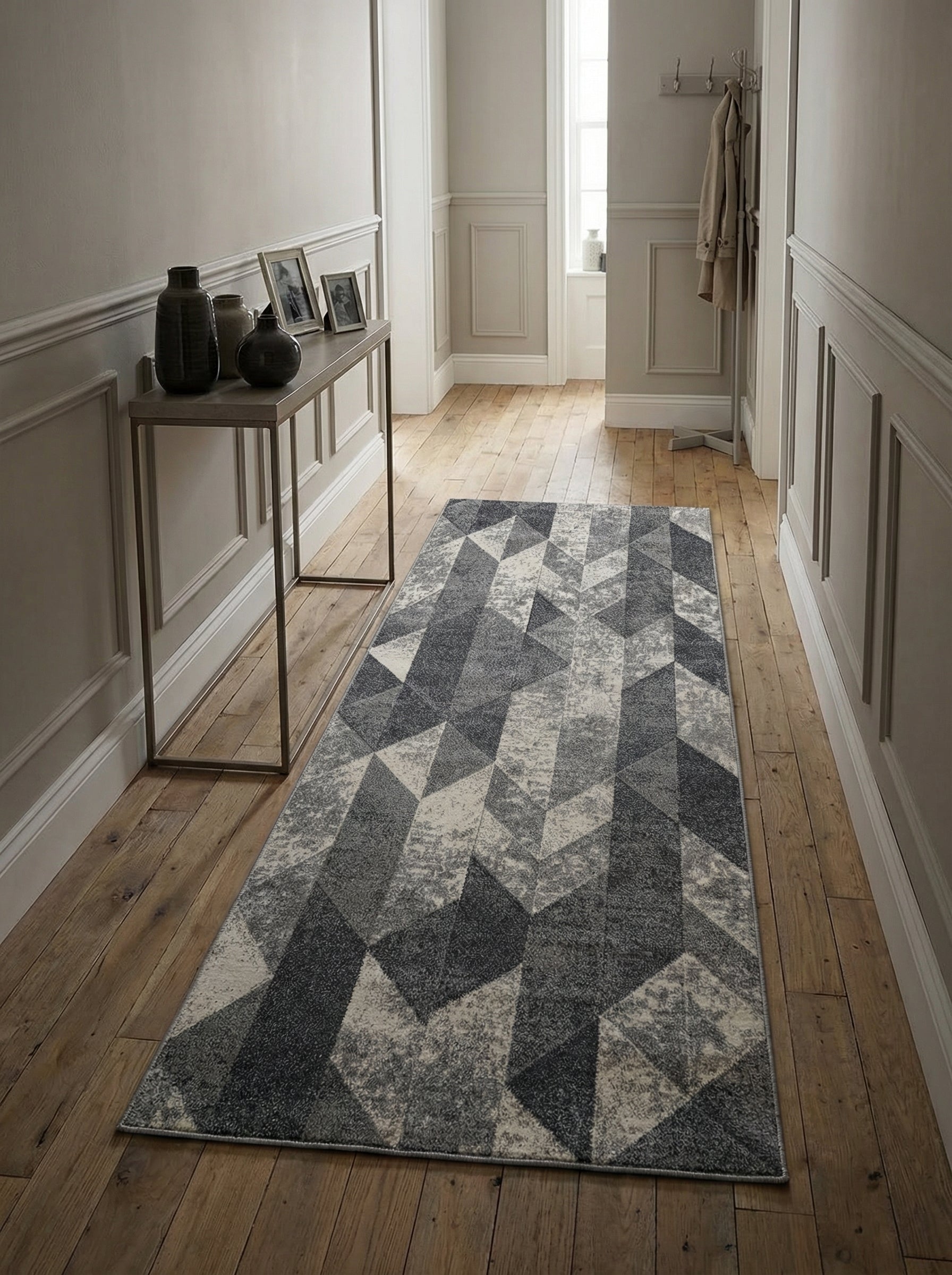 Long tapis gris anthracite, gris clair et blanc cassé aux motifs géométriques, sur un parquet en bois dans un couloir