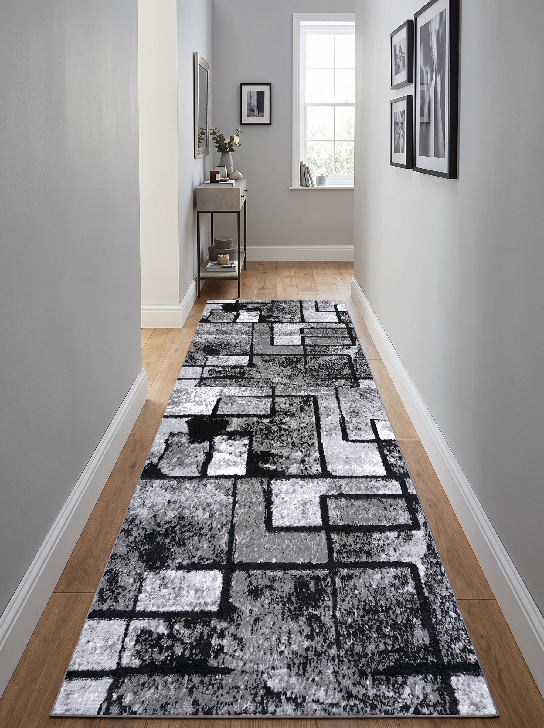 Tapis coureur abstrait gris, blanc et noir aux motifs géométriques et texturés sur un parquet dans un couloir