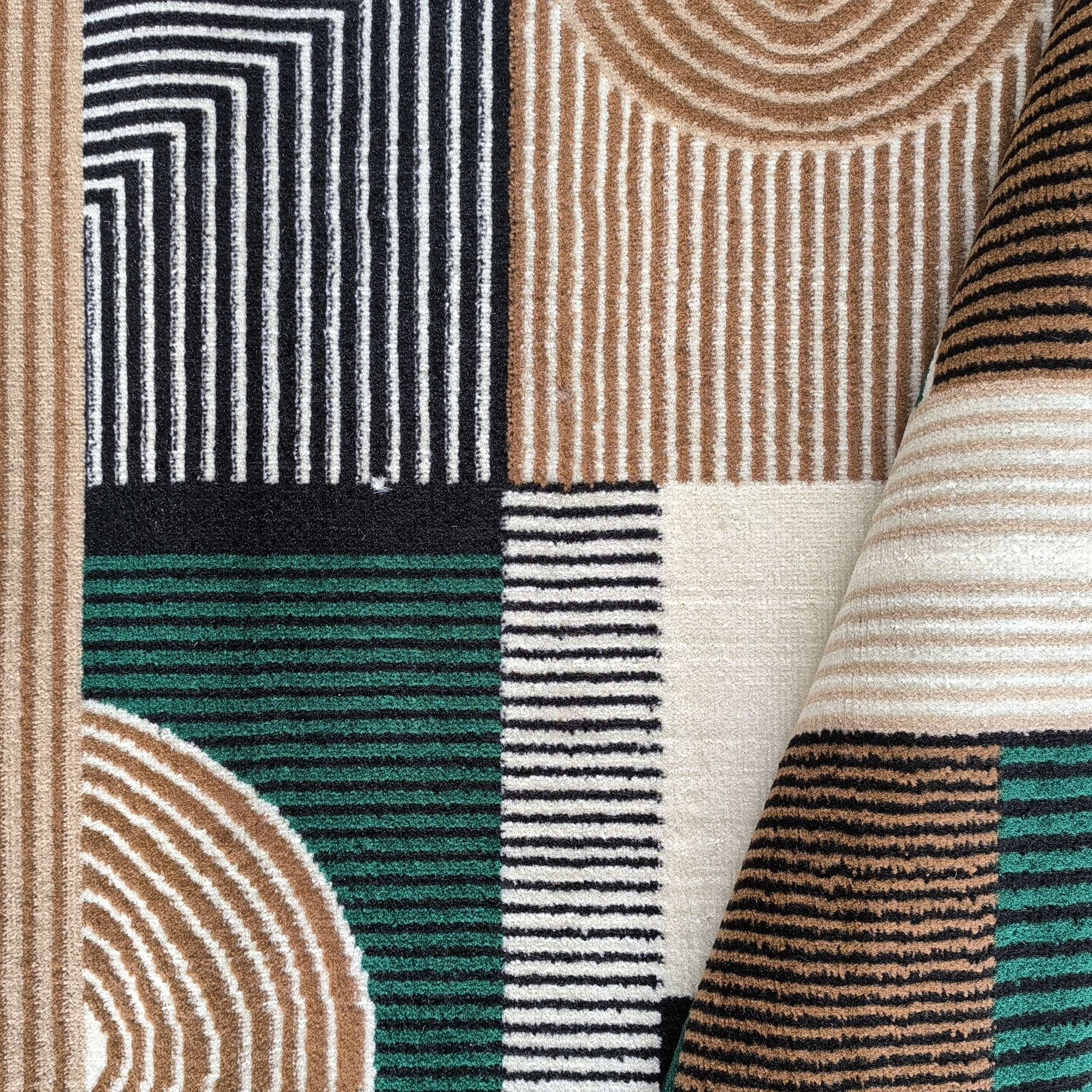 Tapis aux motifs géométriques variés. Il présente des rayures, des blocs de couleur et des formes arrondies en noir, blanc cassé, beige et vert émeraude