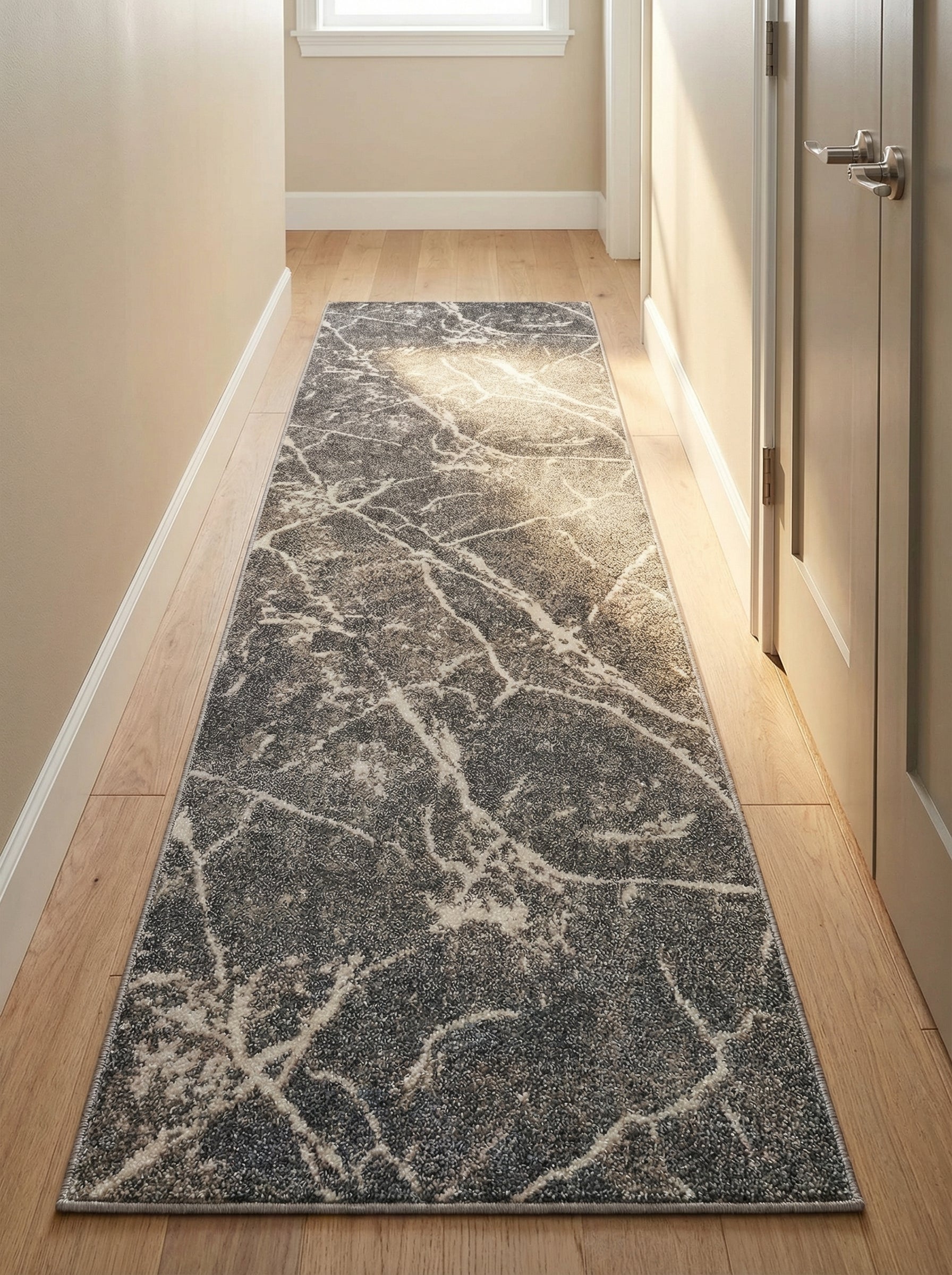 Tapis de couloir rectangulaire aux motifs abstraits blancs et gris clairs sur fond gris foncé, posé sur un parquet clair dans un couloir