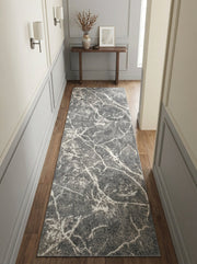 Tapis de couloir long gris foncé avec des motifs sinueux blancs évoquant le marbre, sur un parquet clair dans une entrée