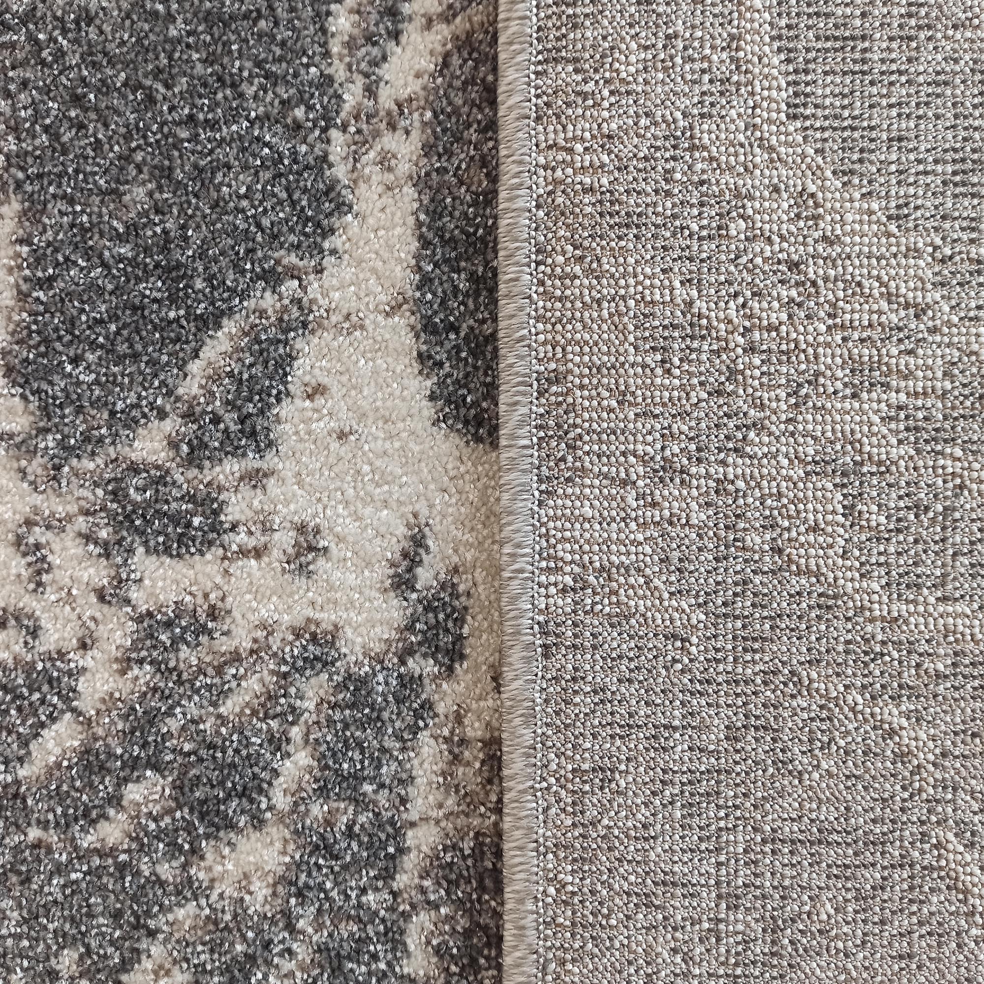 Tapis avec un dessus à motif abstrait gris et crème à texture de poils, et son envers tissé beige clair