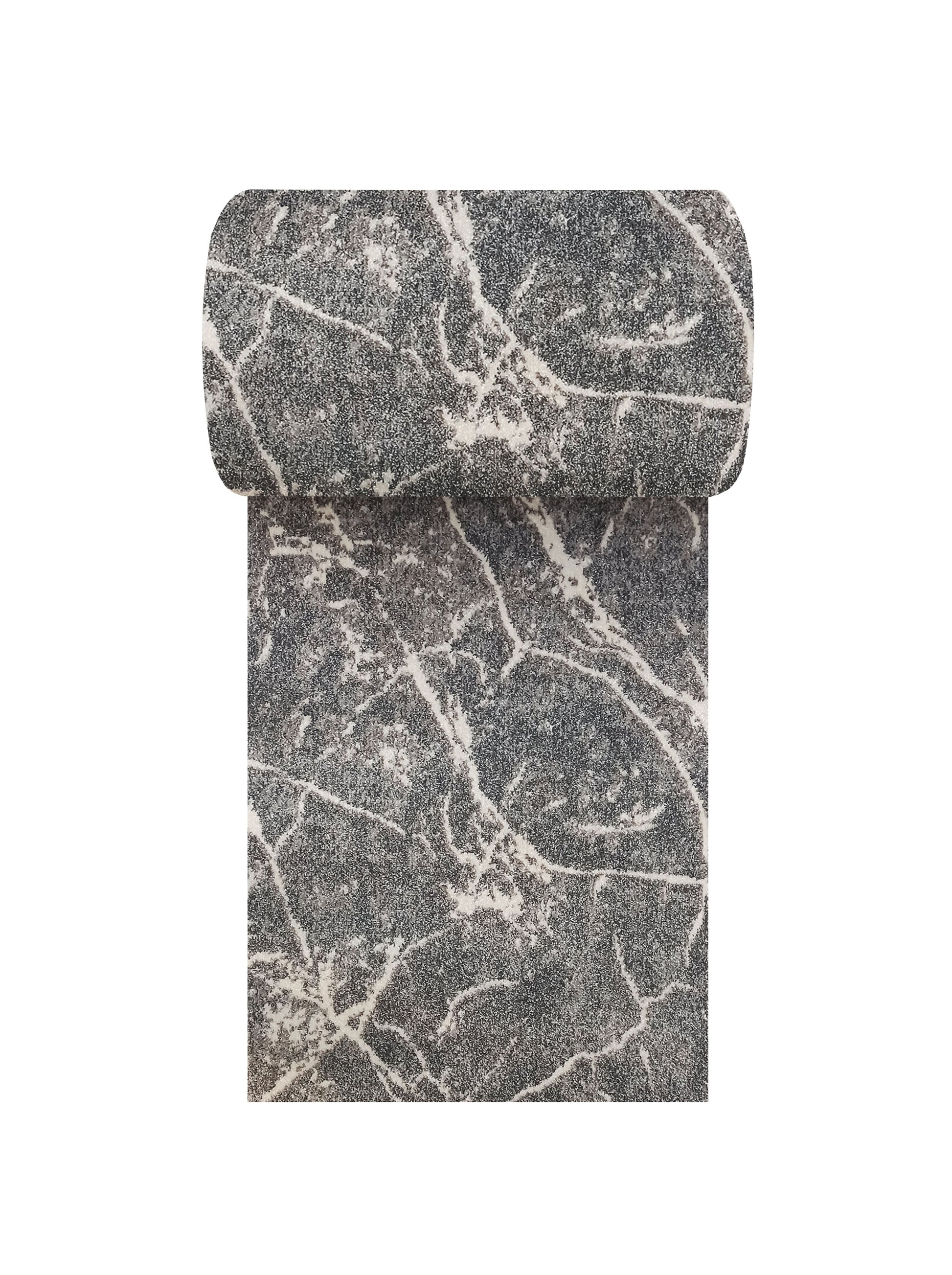 Tapis texturé gris foncé et blanc cassé avec un motif abstrait marbré, partiellement enroulé